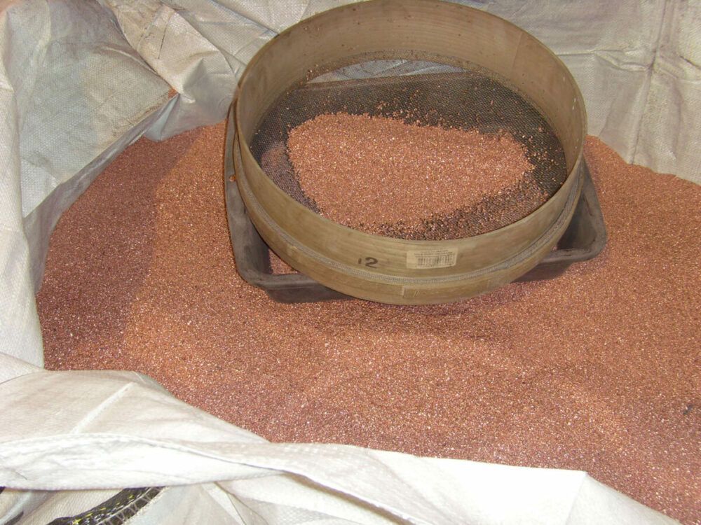 Un tamis posé sur un sac de grenailles de cuivre.