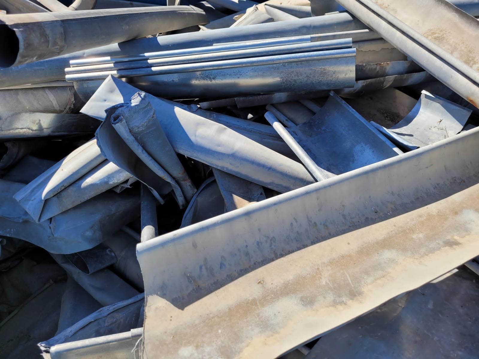 Tas de ferraille grise et tordue, en extérieur.