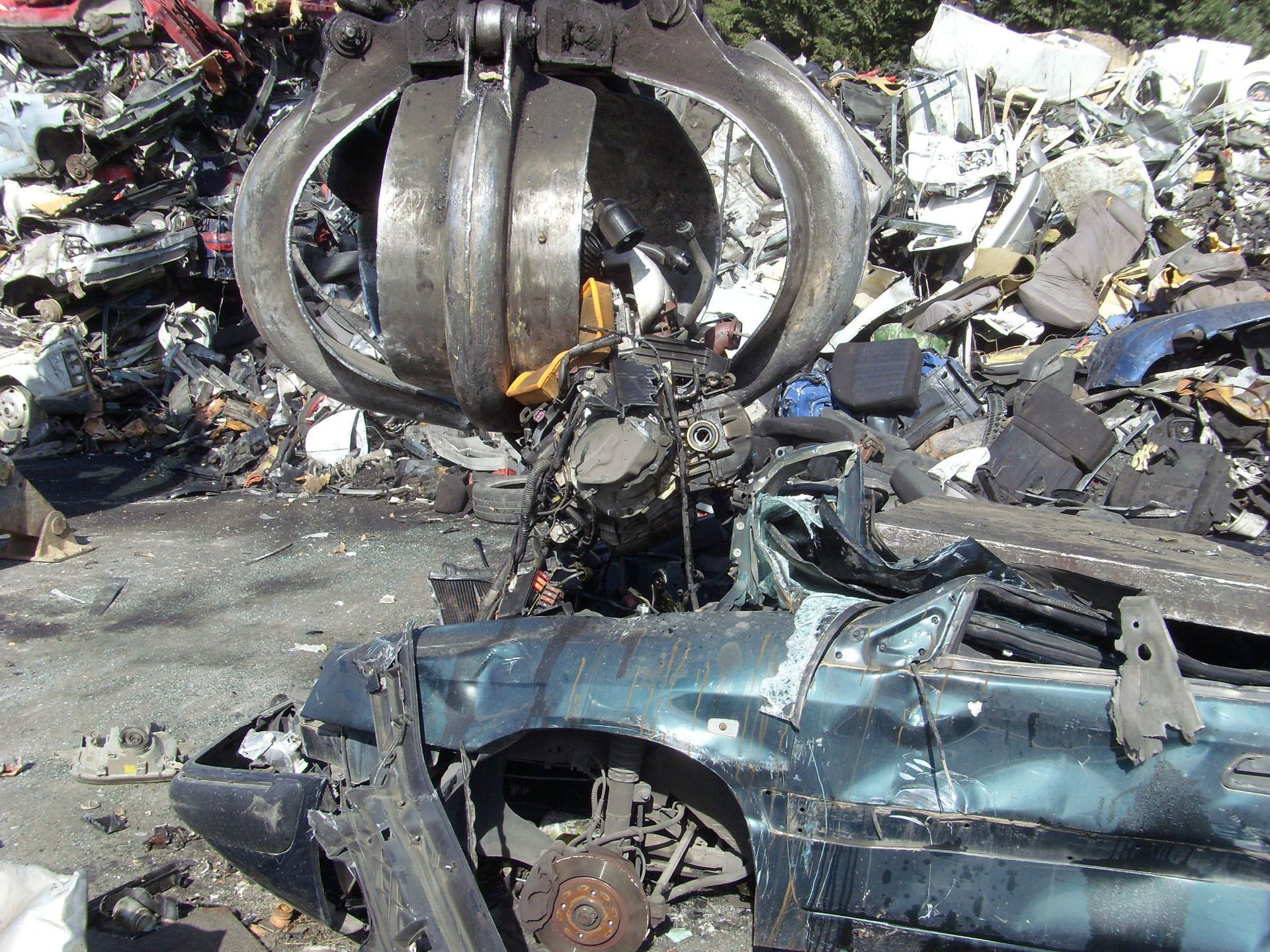 Une machine en forme de griffes broyant une voiture dans une casse.