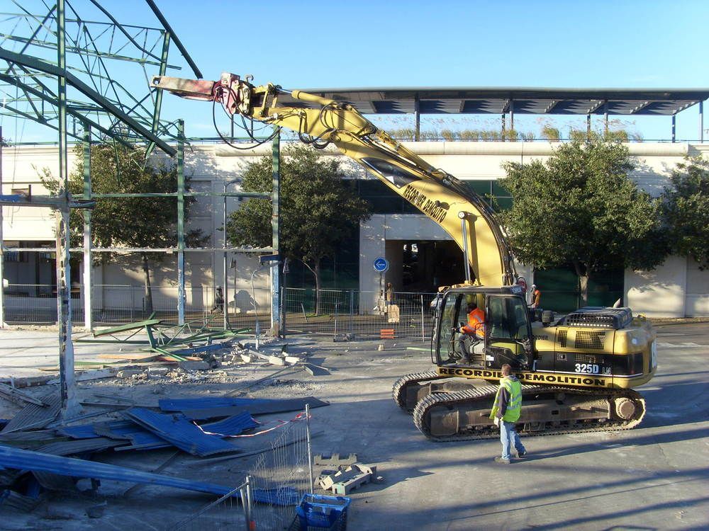 Une excavatrice de démolition démolit la structure d'un bâtiment en extérieur.