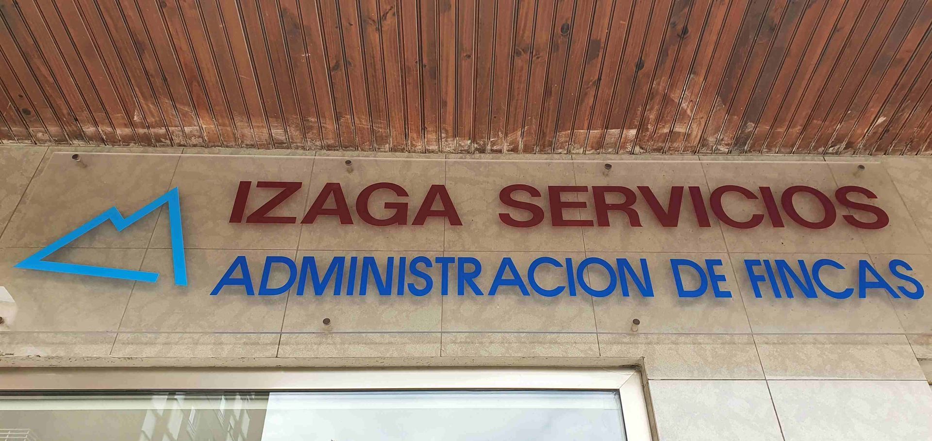 A sign on the side of a building that says izaga servicios administración de fincas