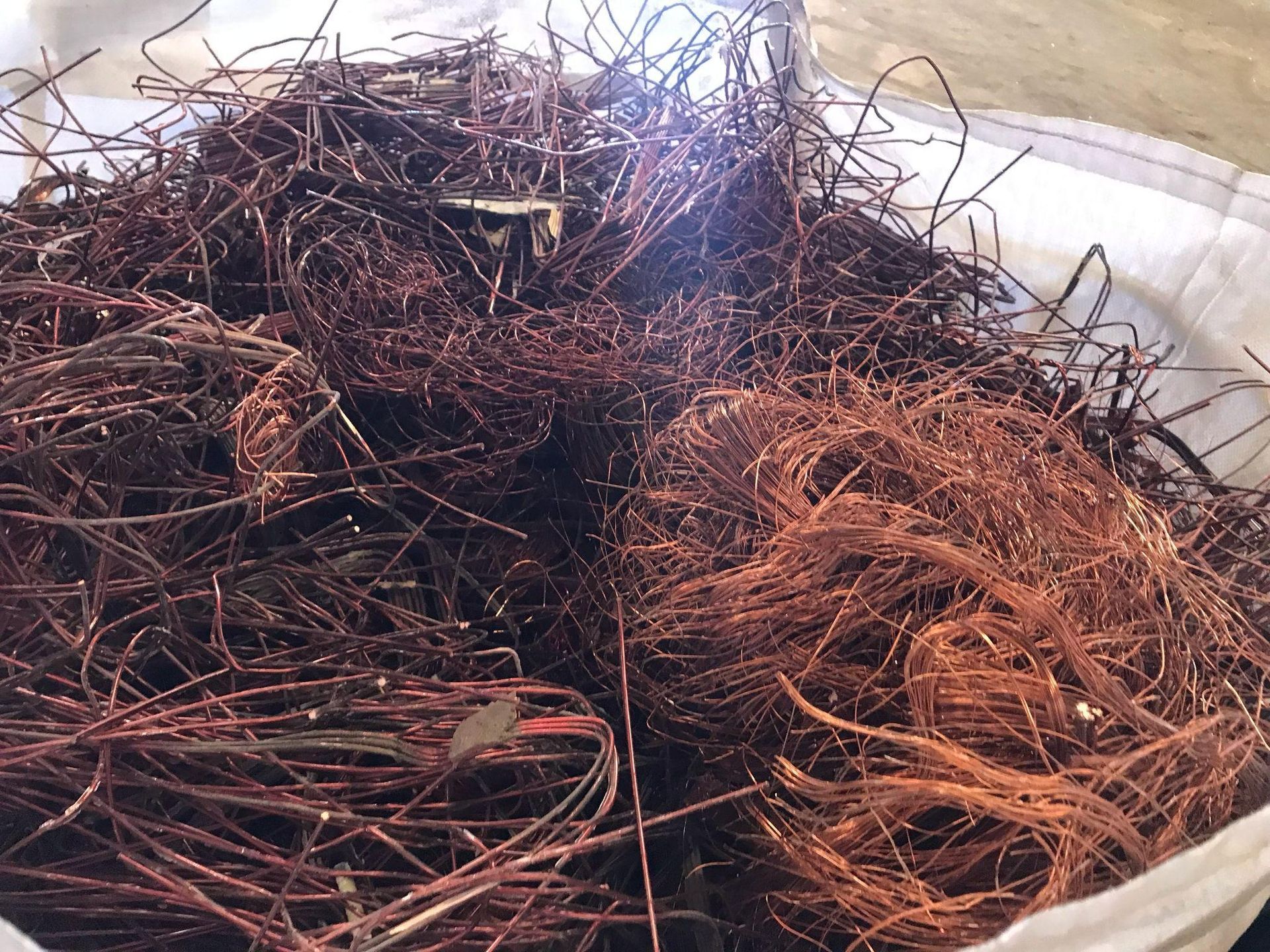 Una pila de alambre de cobre reposa en un cubo blanco.