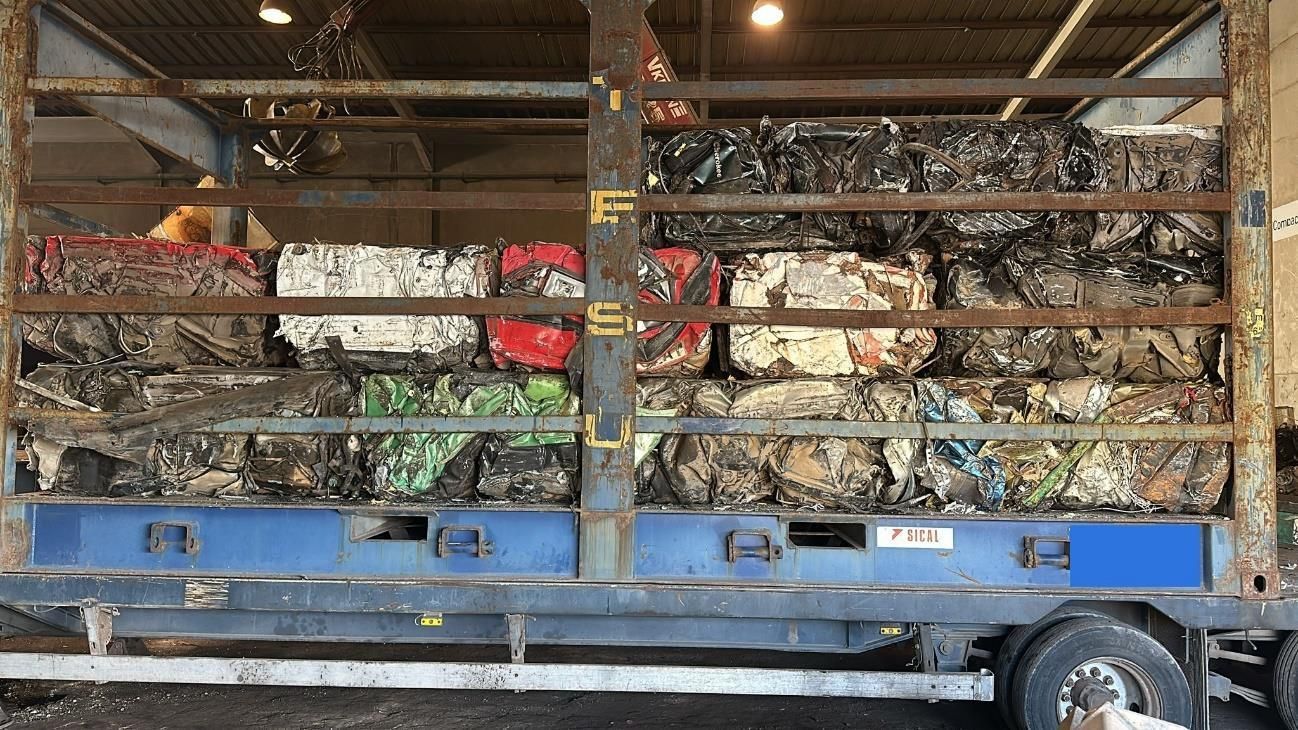 Un montón de coches viejos y oxidados están tirados en el suelo.