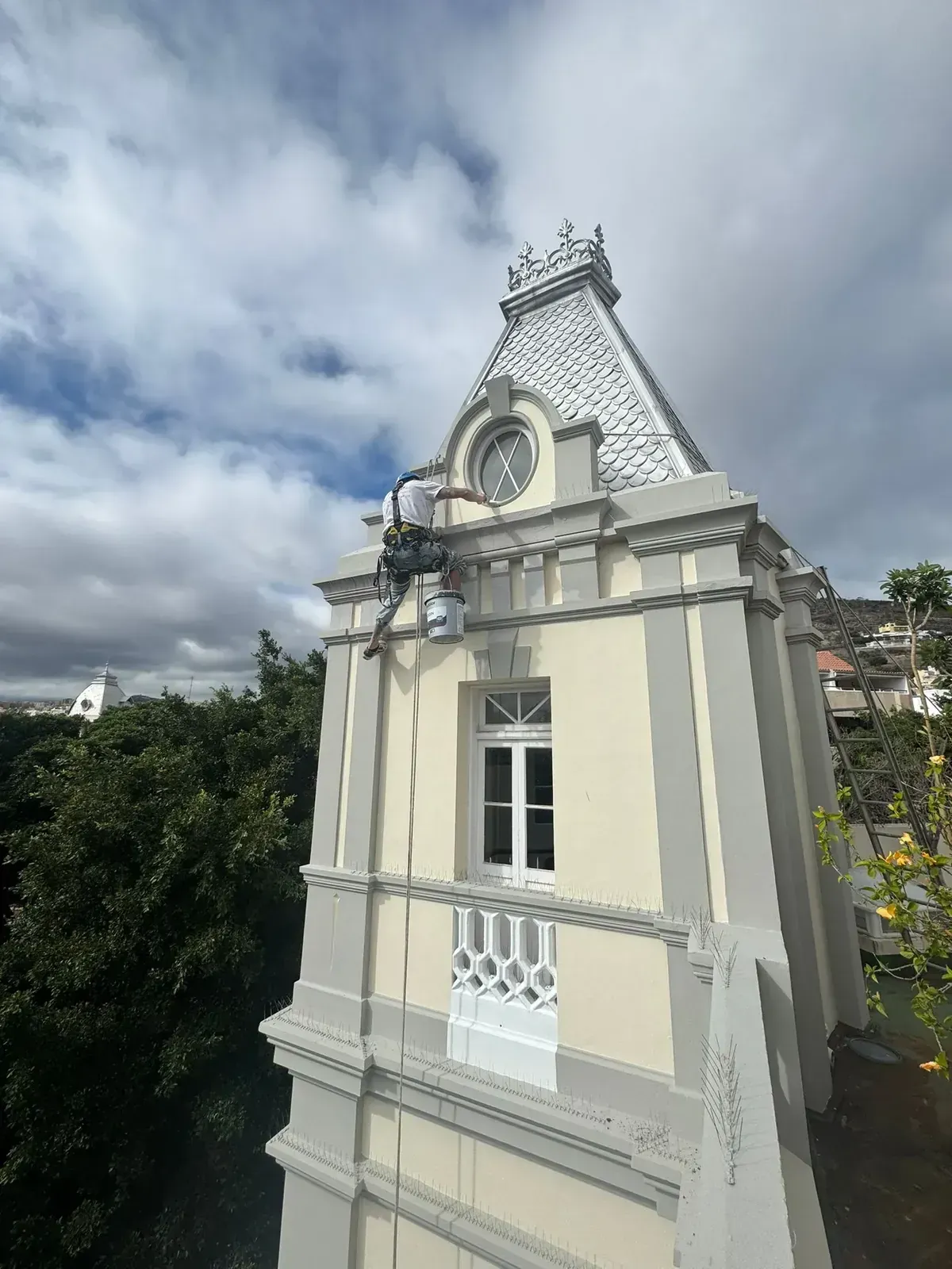 Fachada ornamentada de color crema y blanco con balcón bajo un cielo nublado.