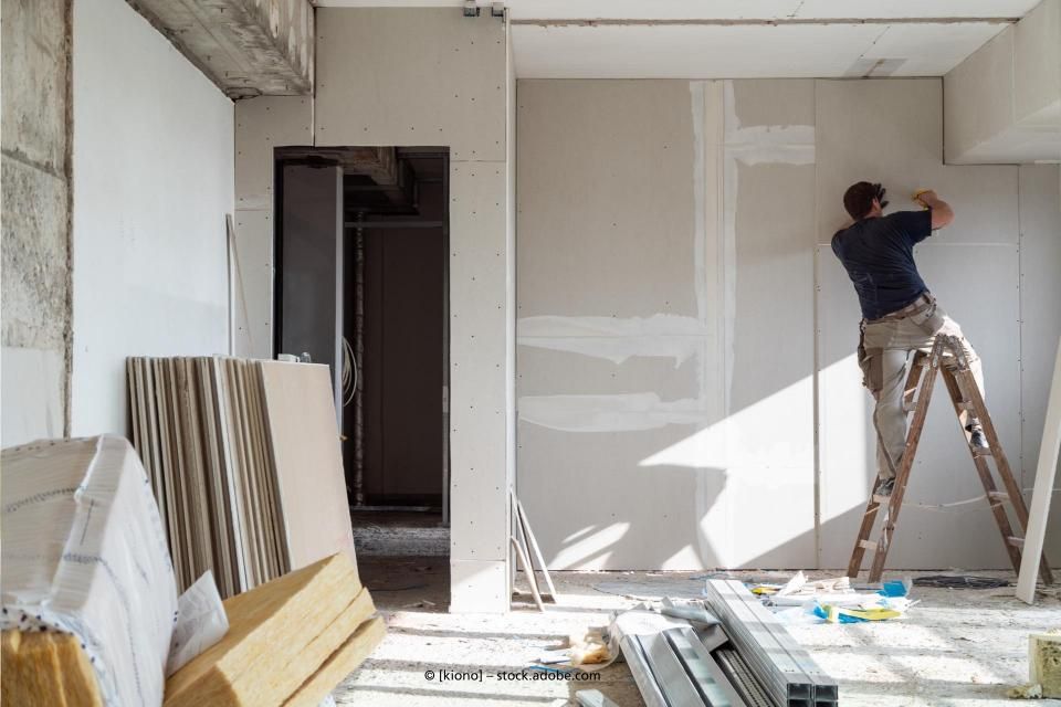 Ein Mann steht auf einer Leiter in einem Raum im Bau.