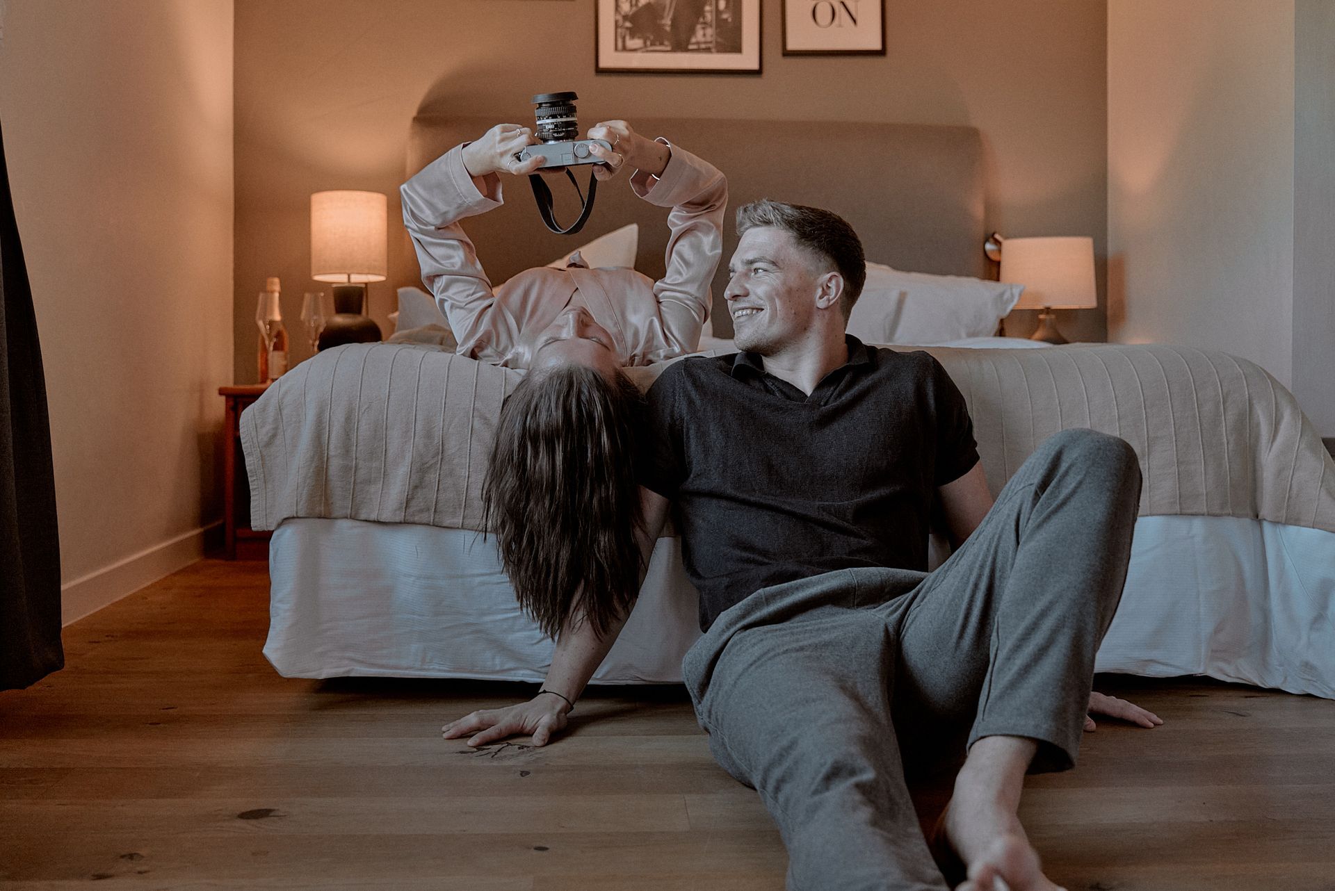 Ein Mann und eine Frau sitzen vor einem Bett auf dem Boden.
