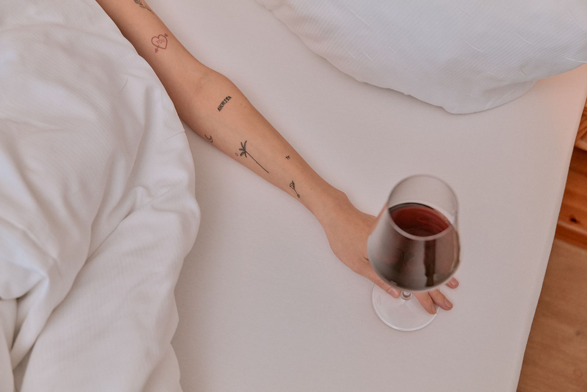 Eine Frau liegt auf einem Bett und hält ein Glas Wein in der Hand.
