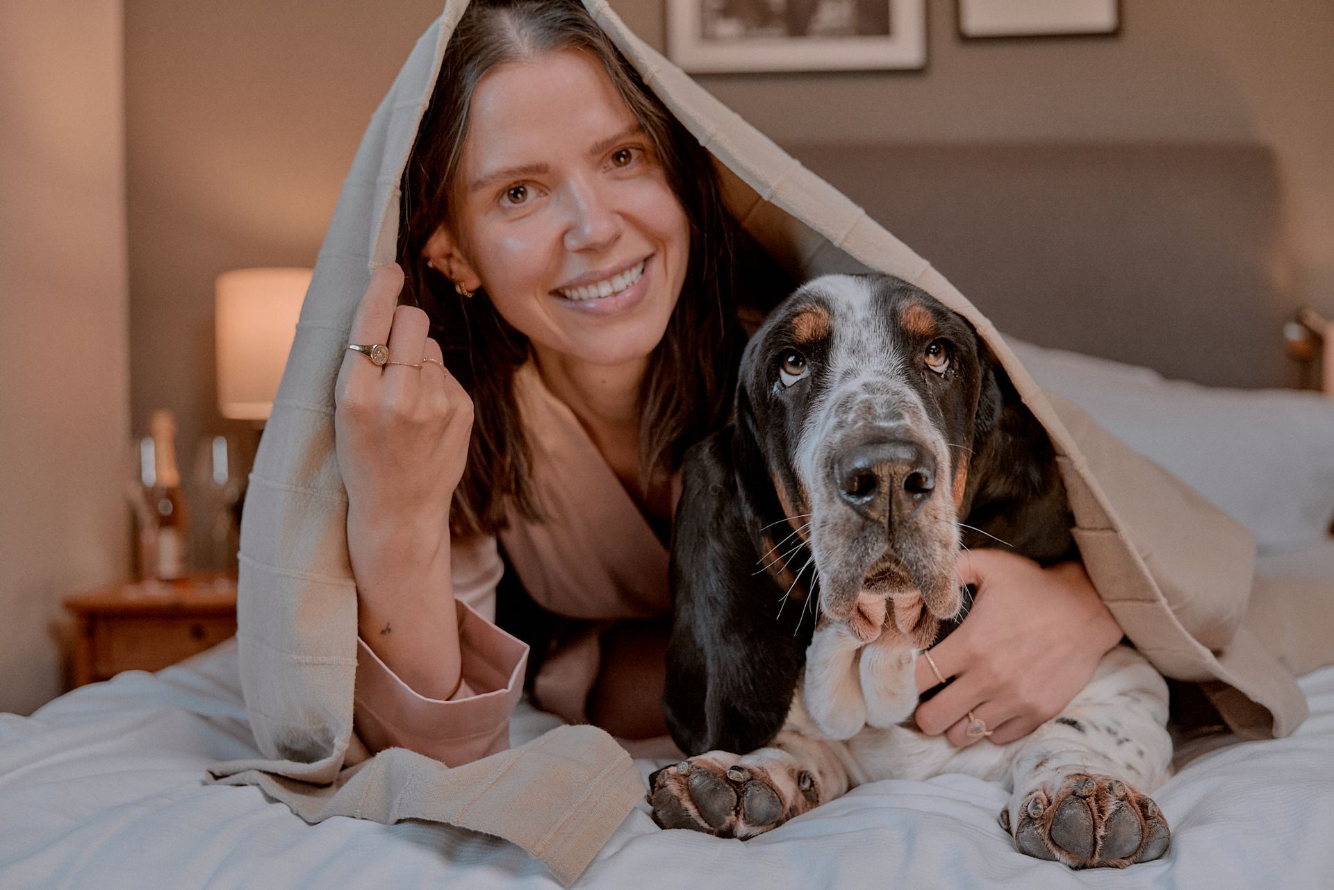 Eine Frau liegt auf einem Bett und hat einen Hund unter der Decke.