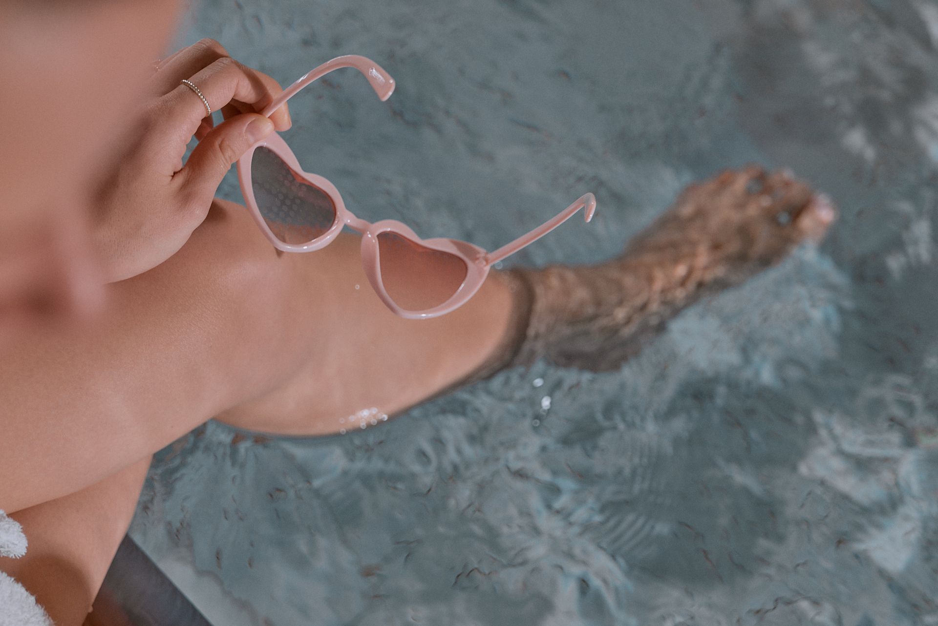 Eine Frau mit einer rosa Sonnenbrille in Herzform nimmt ein Bad in einem Whirlpool.