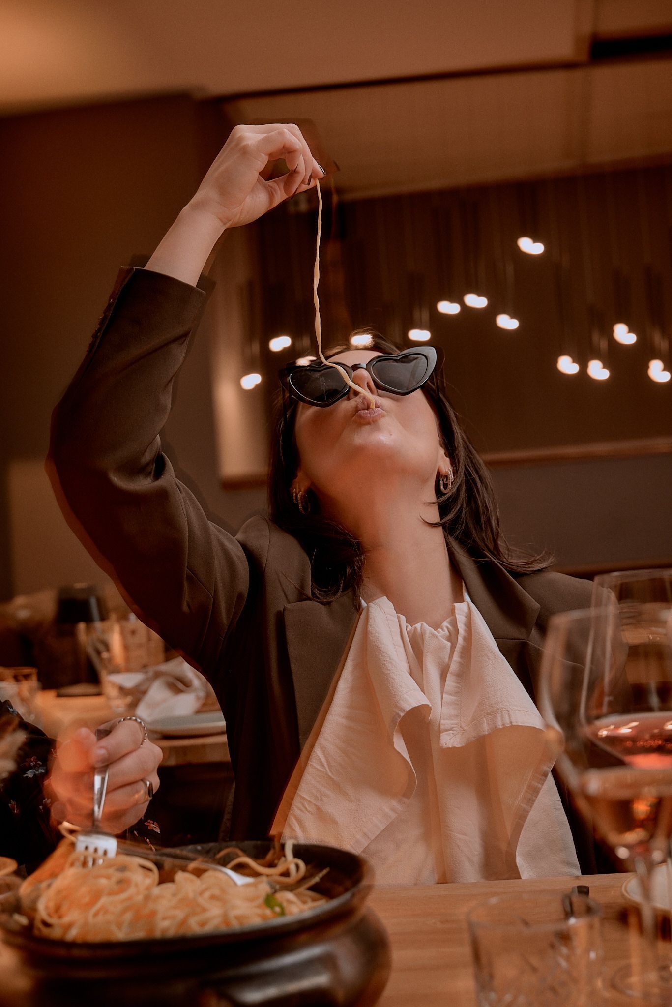 Eine Frau isst in einem Restaurant Nudeln mit einer Gabel.