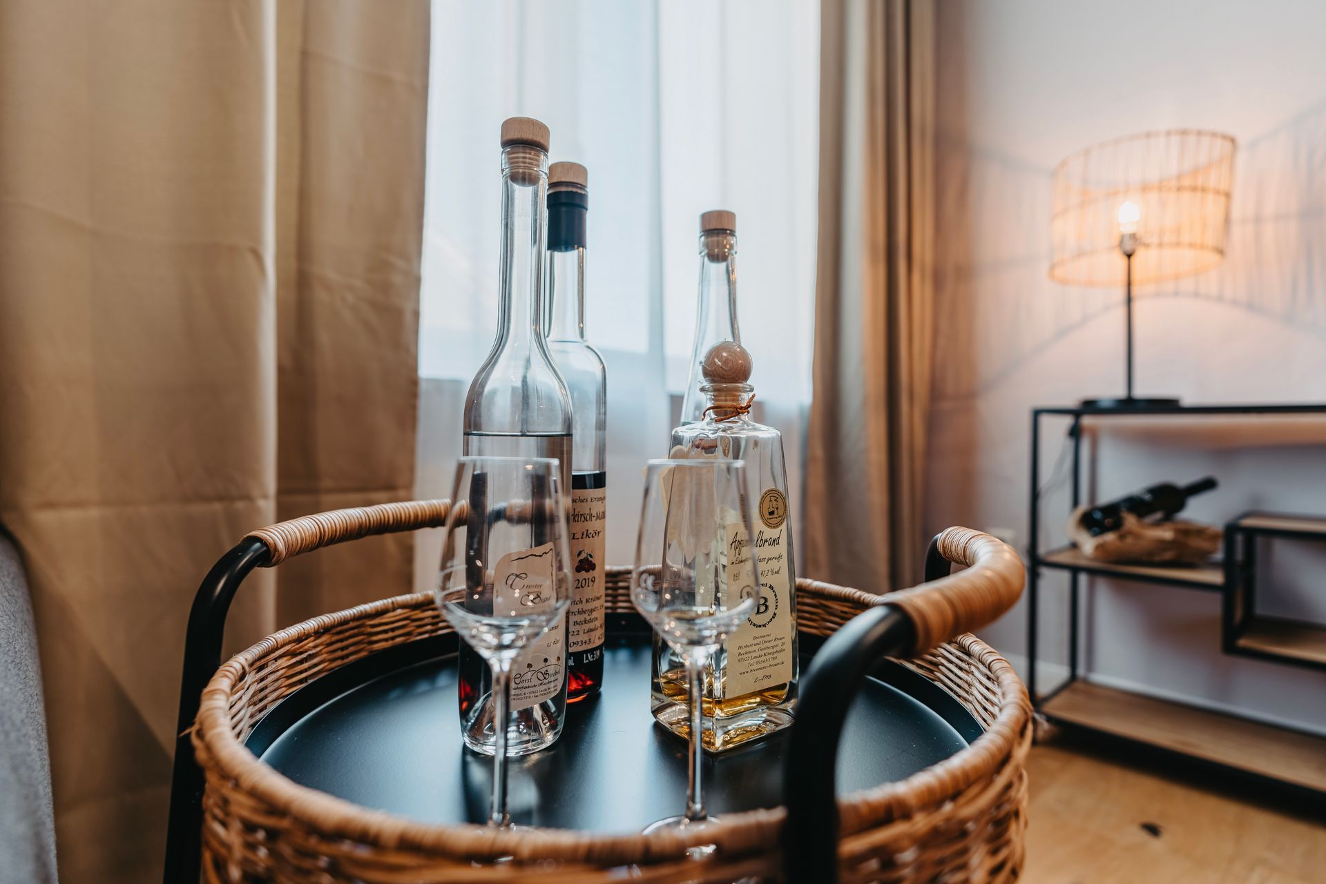 Ein Korbtablett mit Weinflaschen und Gläsern darauf.