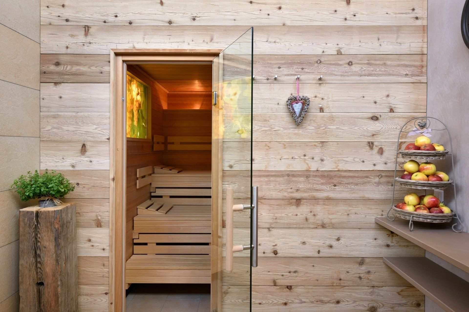 Eine Holzsauna mit Glastür und einem Herz an der Wand.