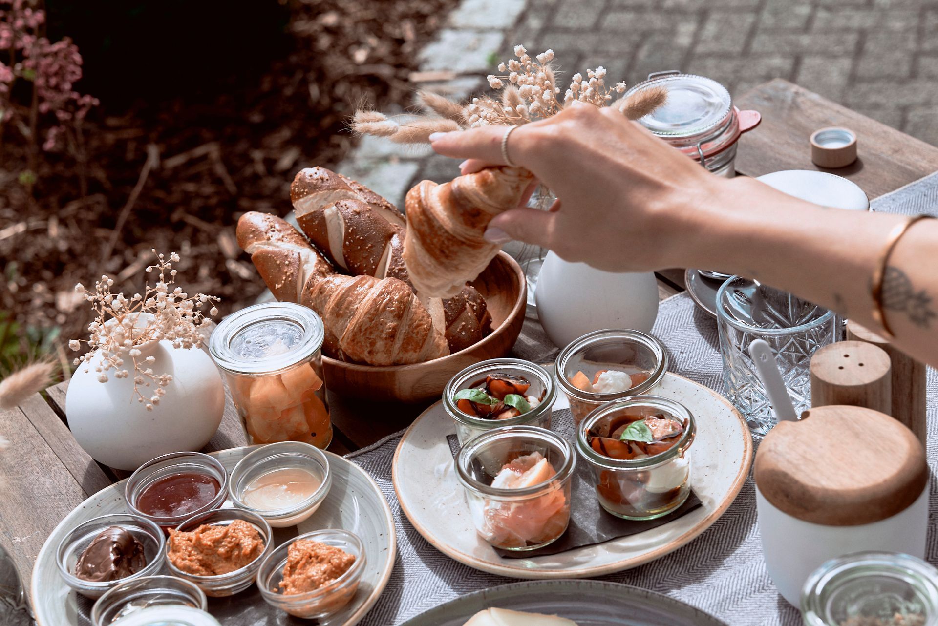 Eine Person isst an einem Tisch ein Croissant am Stiel.