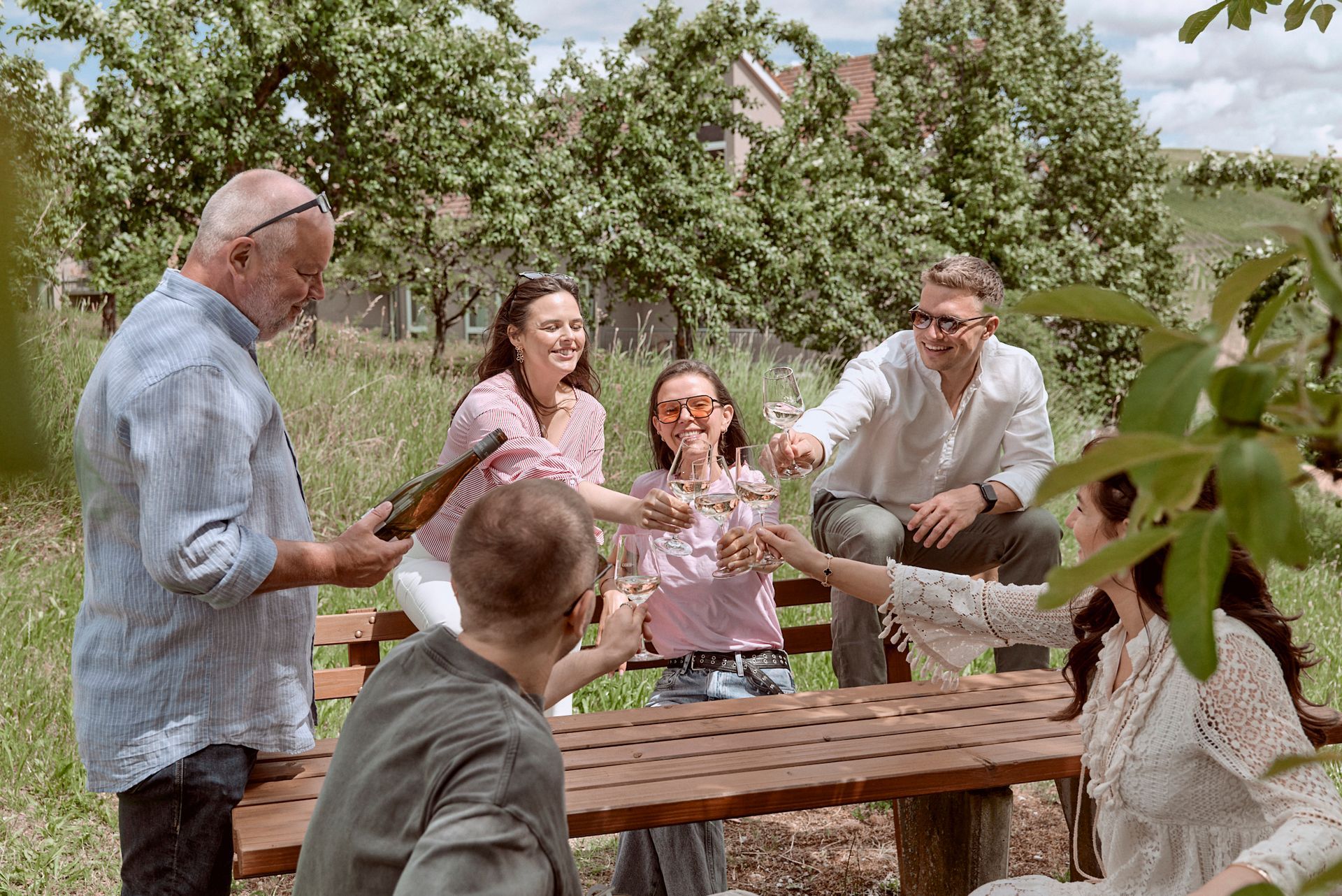 Eine Frau sitzt auf einer Mauer auf einem Feld und hält etwas zu trinken.