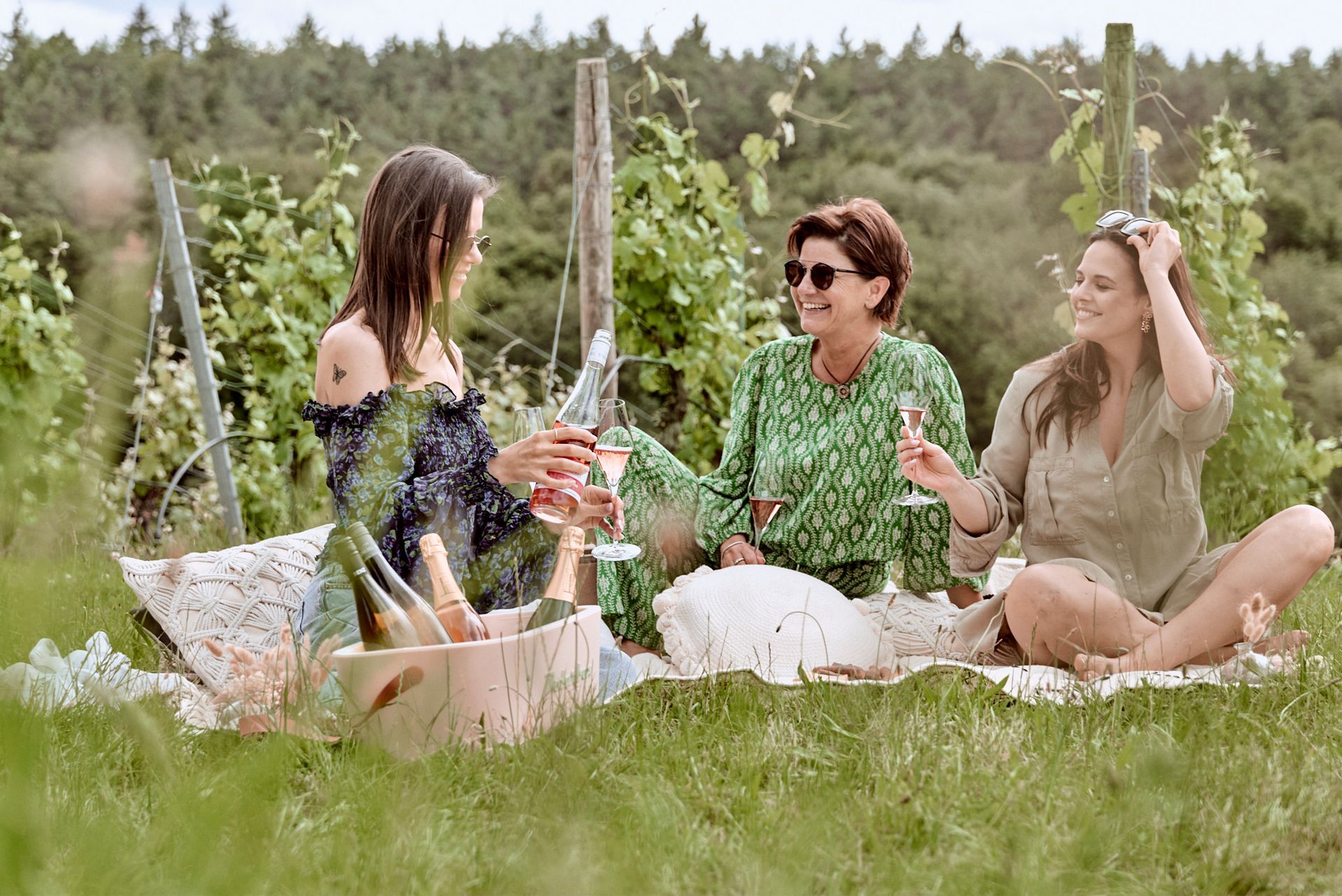 Drei Frauen machen ein Picknick in einem Weinberg.