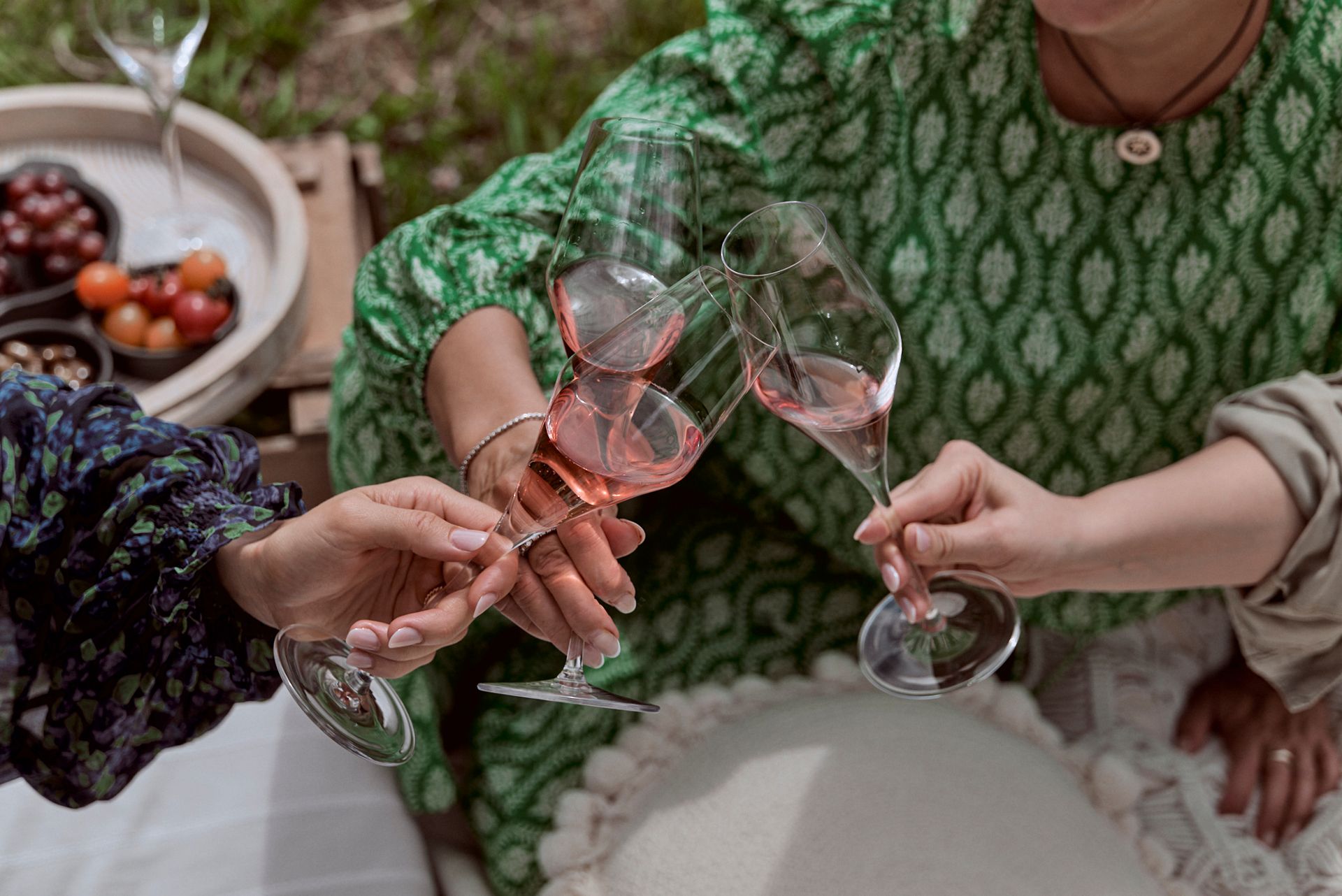 Eine Gruppe Frauen stößt bei einem Picknick mit Weingläsern an.