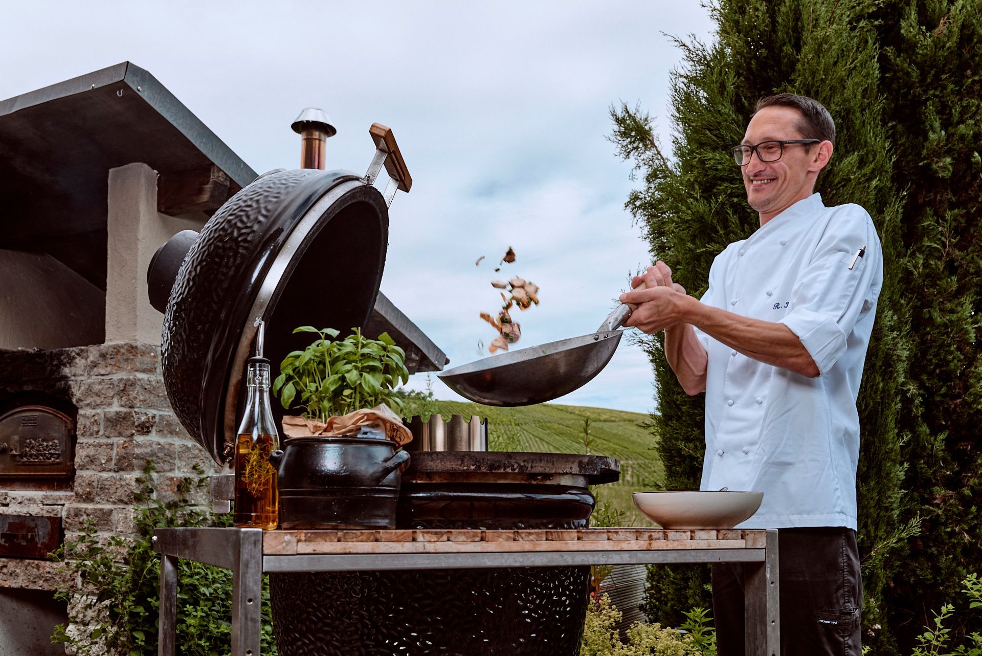 Ein Mann in Kochuniform bereitet Essen auf einem Grill zu.