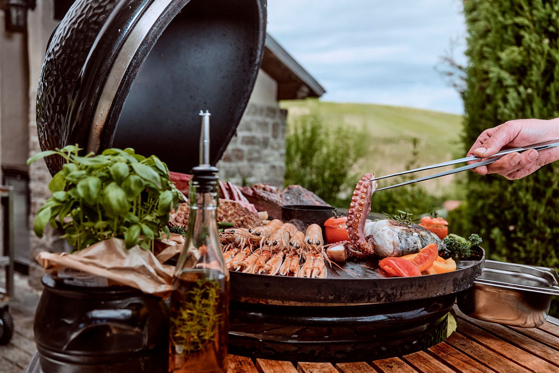 Eine Person bereitet Essen auf einem Grill auf einem Holztisch zu.