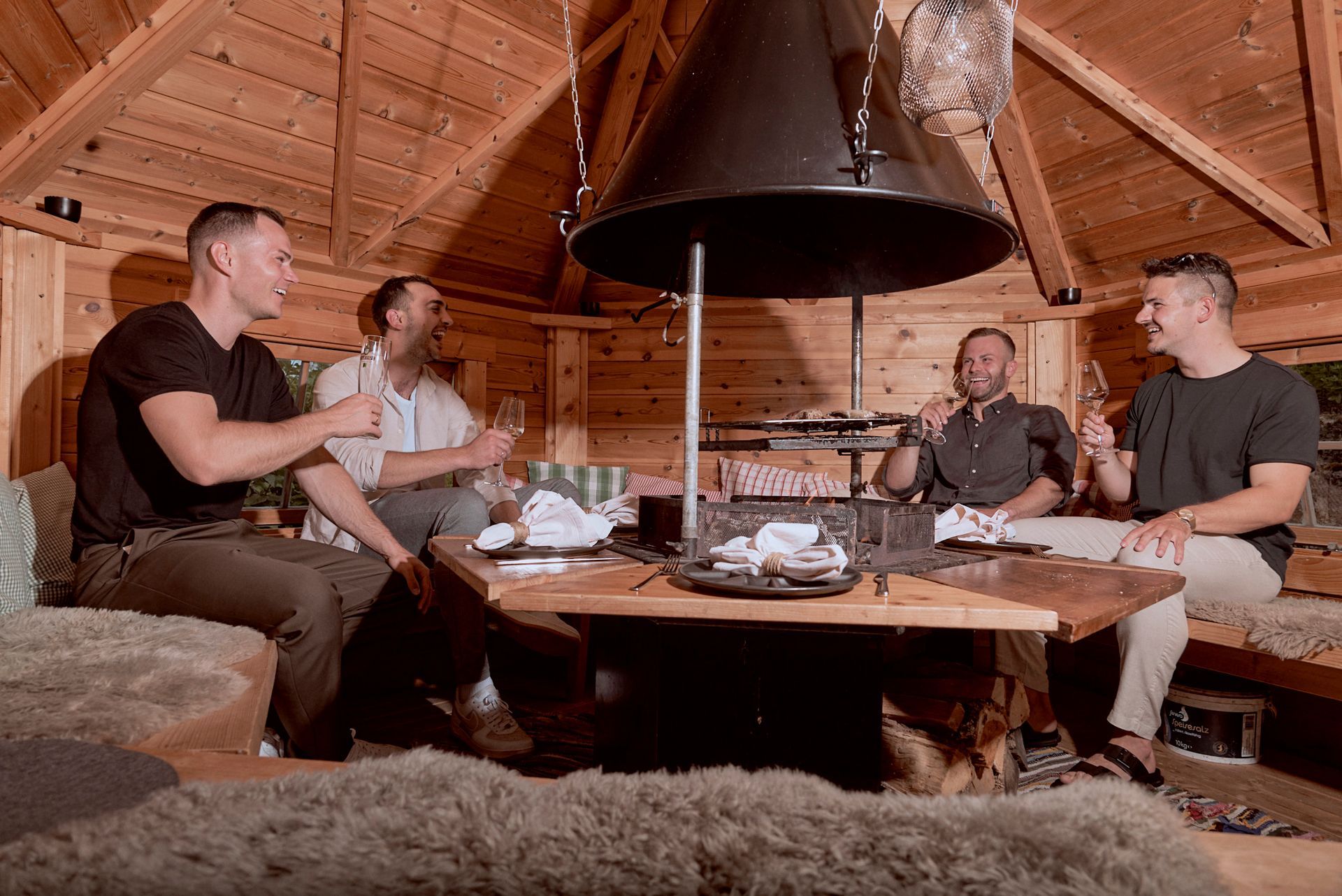 Eine Gruppe Männer sitzt in einer Holzhütte um einen Tisch.