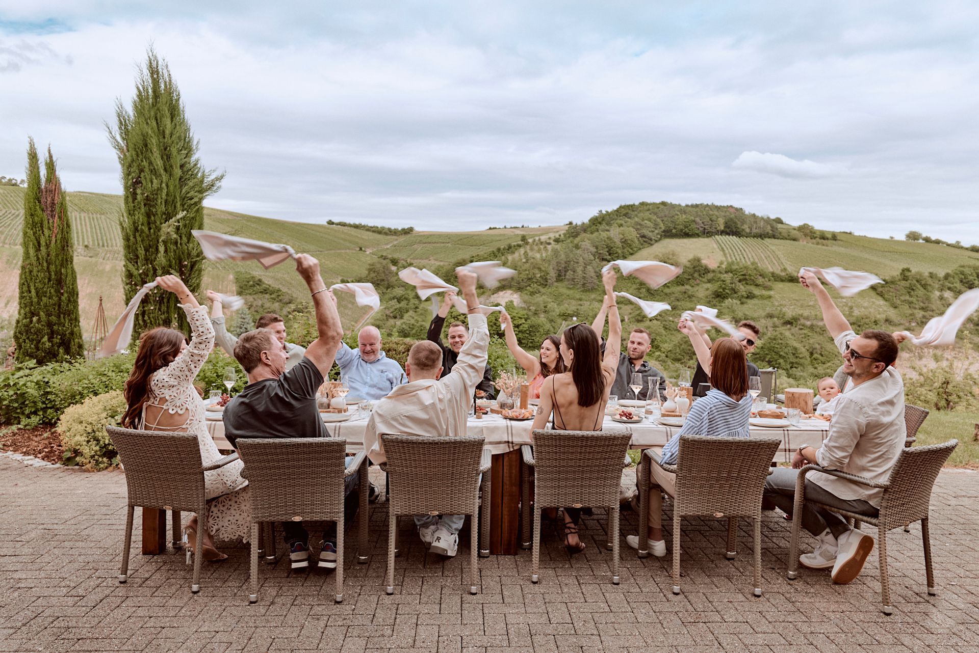 Eine Gruppe von Leuten sitzt mit erhobenen Händen an einem Tisch.