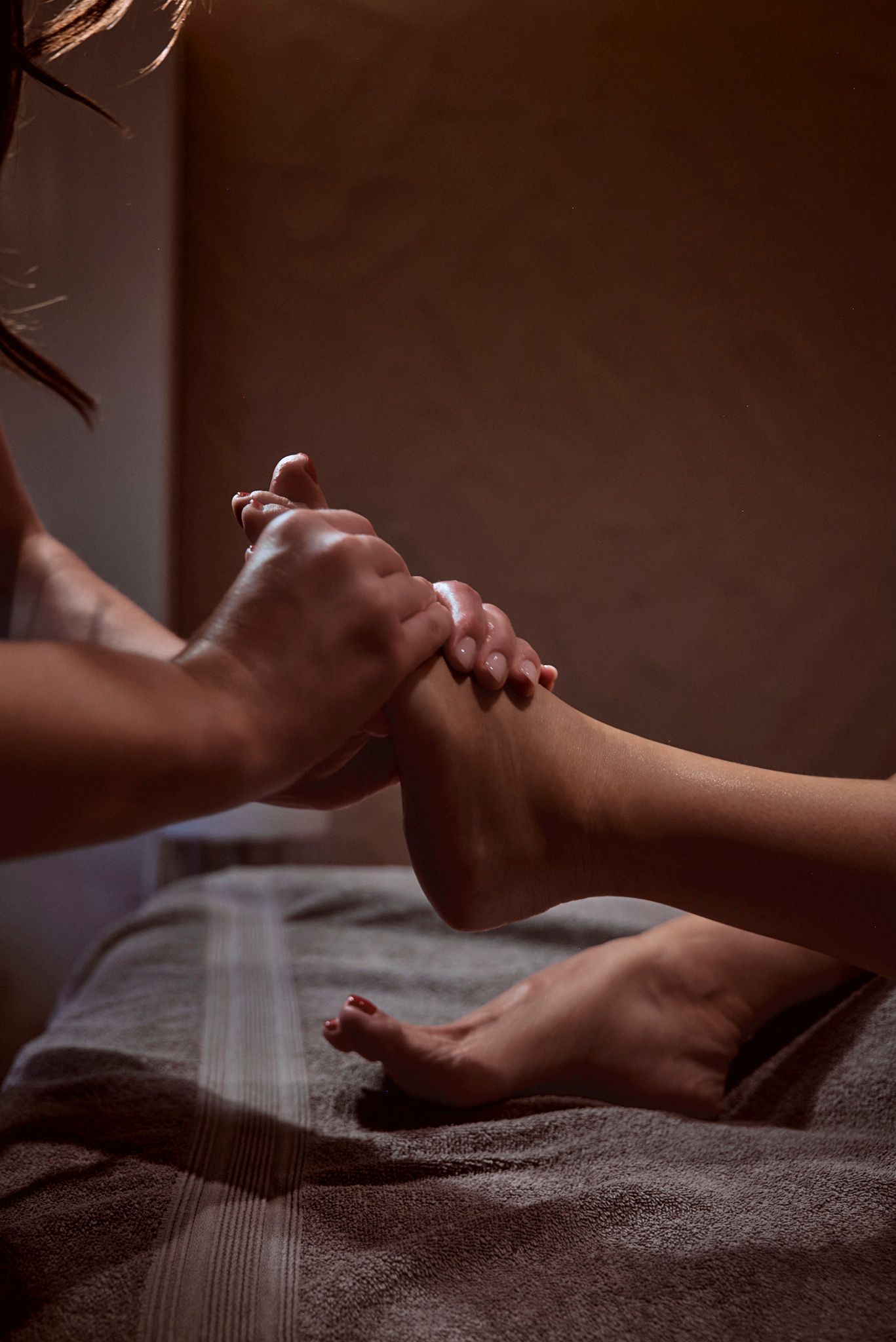 Eine Frau bekommt auf einem Bett eine Fußmassage.