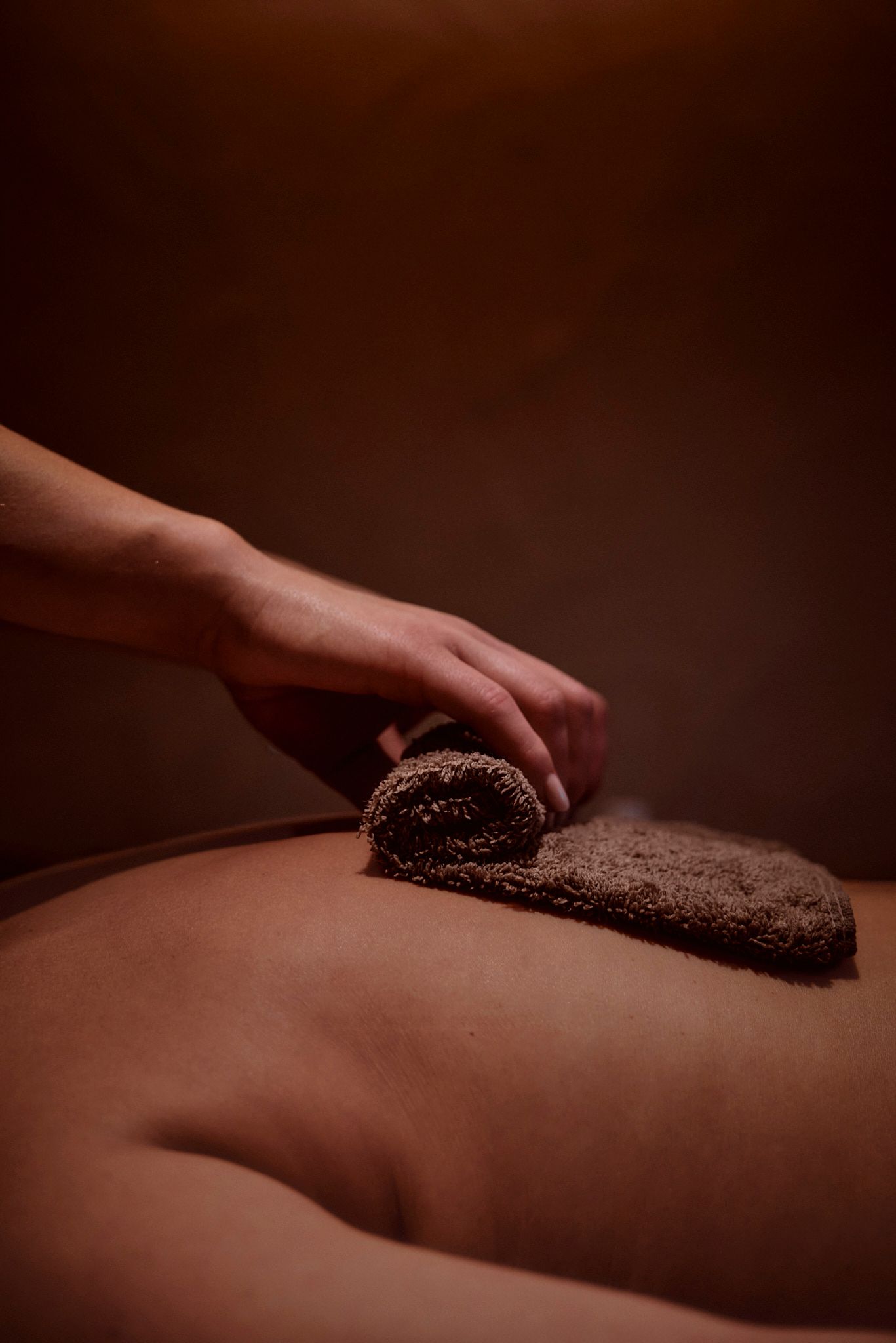 Eine Person bekommt eine Massage mit einem Handtuch auf dem Rücken.
