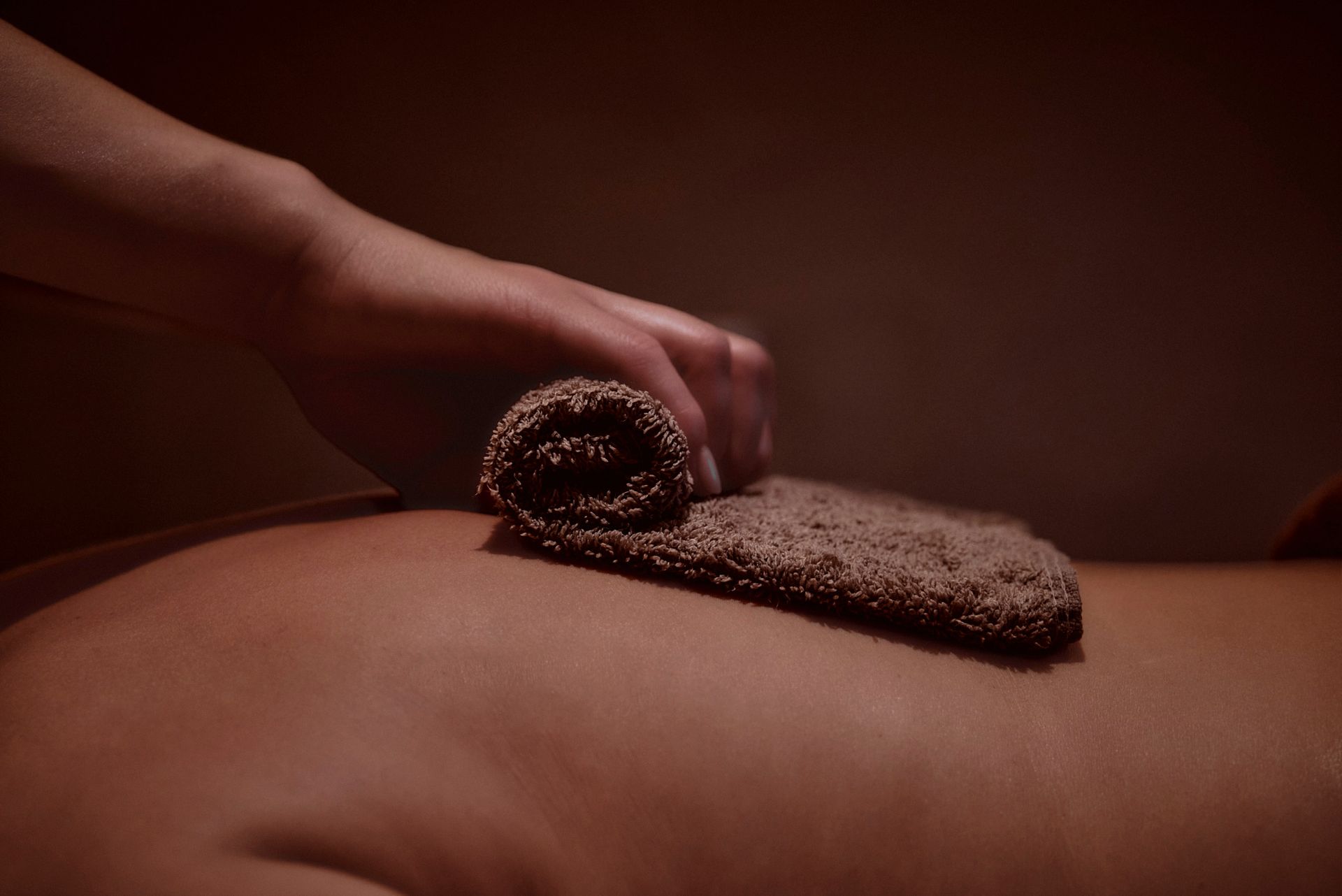 Eine Person bekommt eine Massage mit einem Handtuch auf dem Rücken.