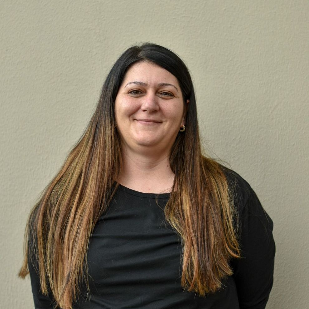 Eine Frau mit langen Haaren lächelt und trägt ein schwarzes Hemd