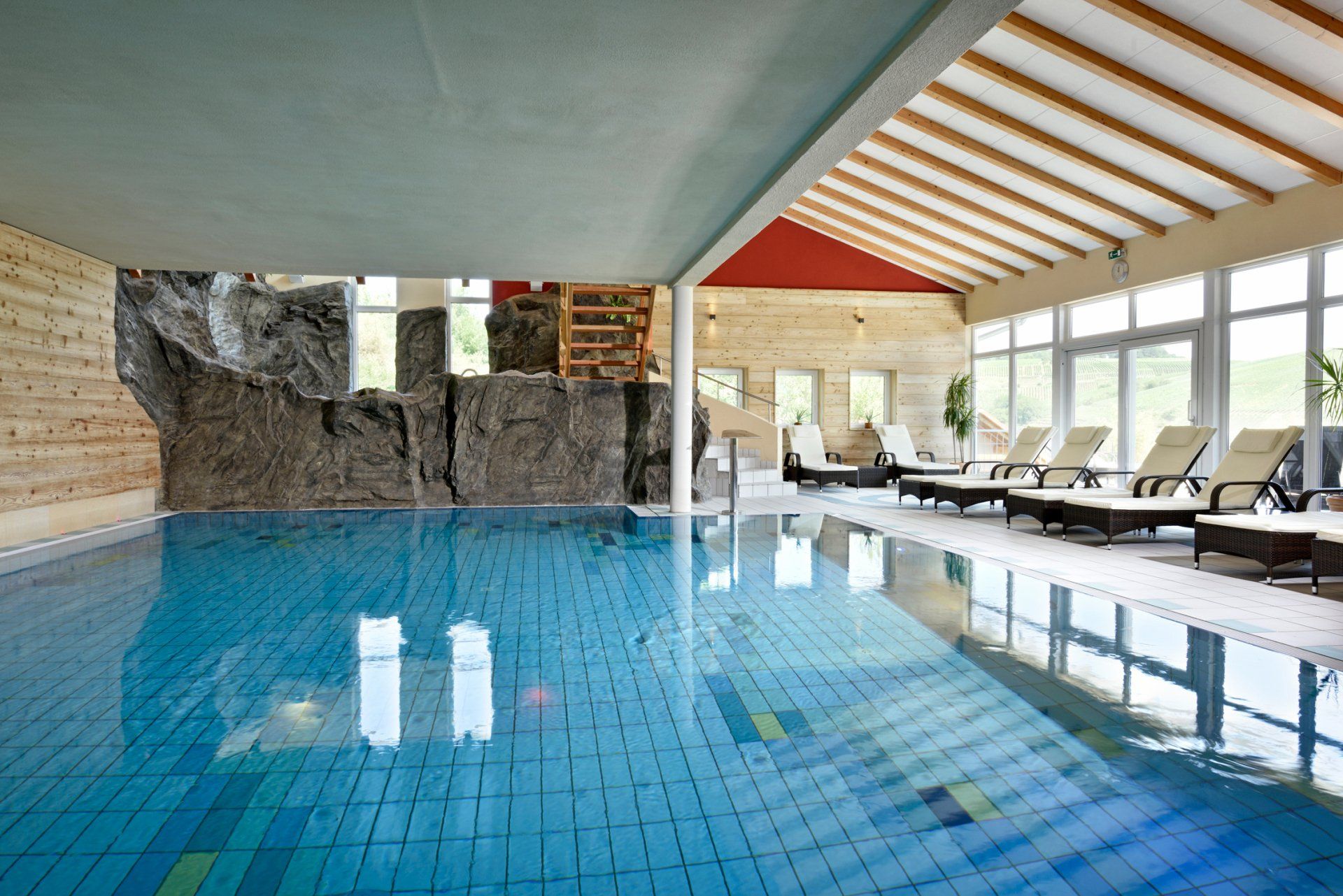 Ein großes Hallenbad mit Liegestühlen drumherum