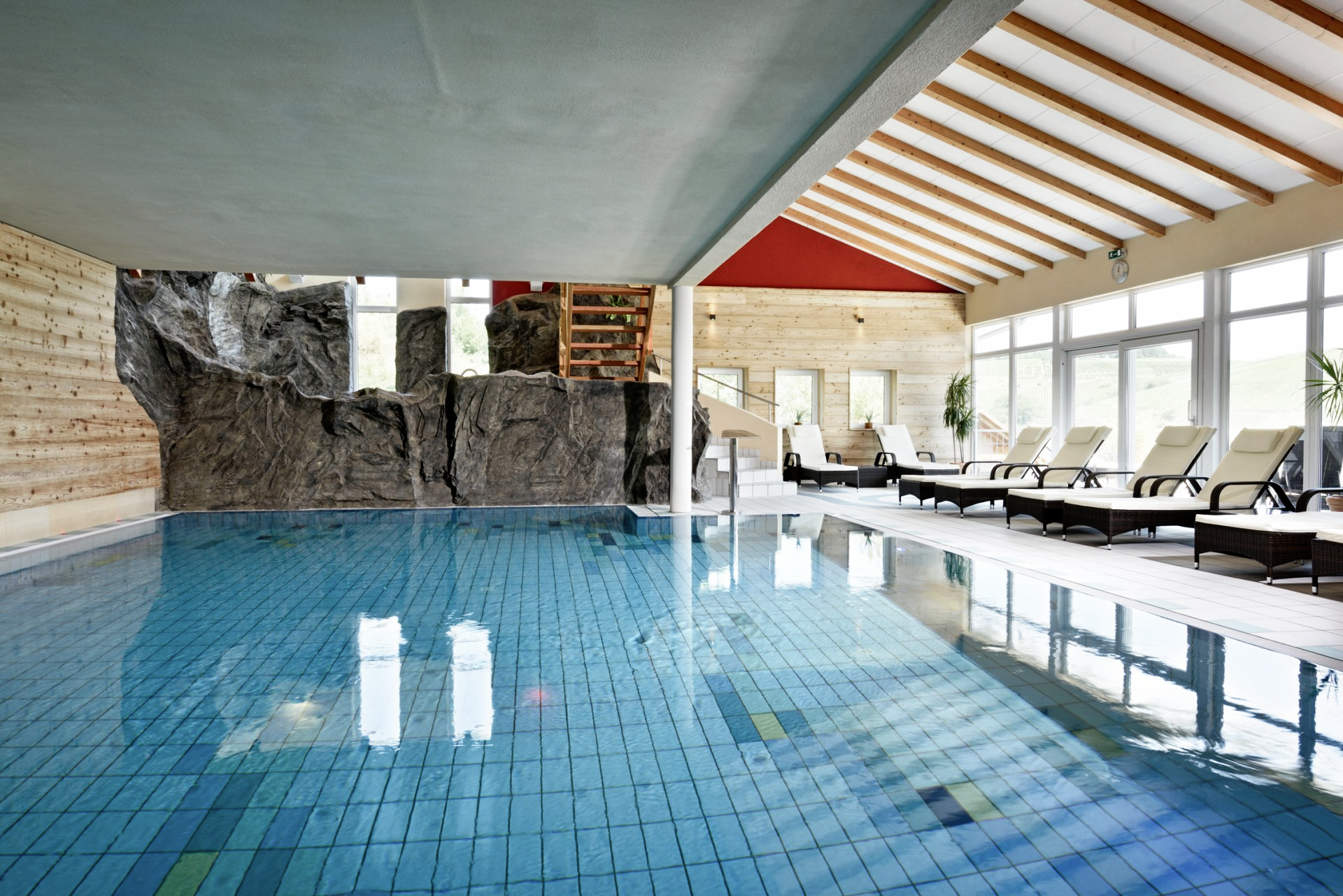 Ein großes Hallenbad mit Liegestühlen drumherum