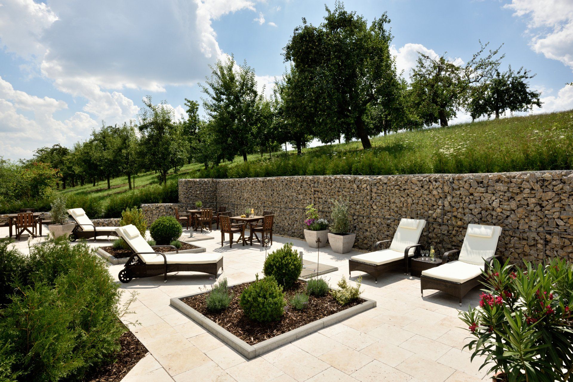 Eine Terrasse mit Stühlen, Tischen und Bäumen im Hintergrund