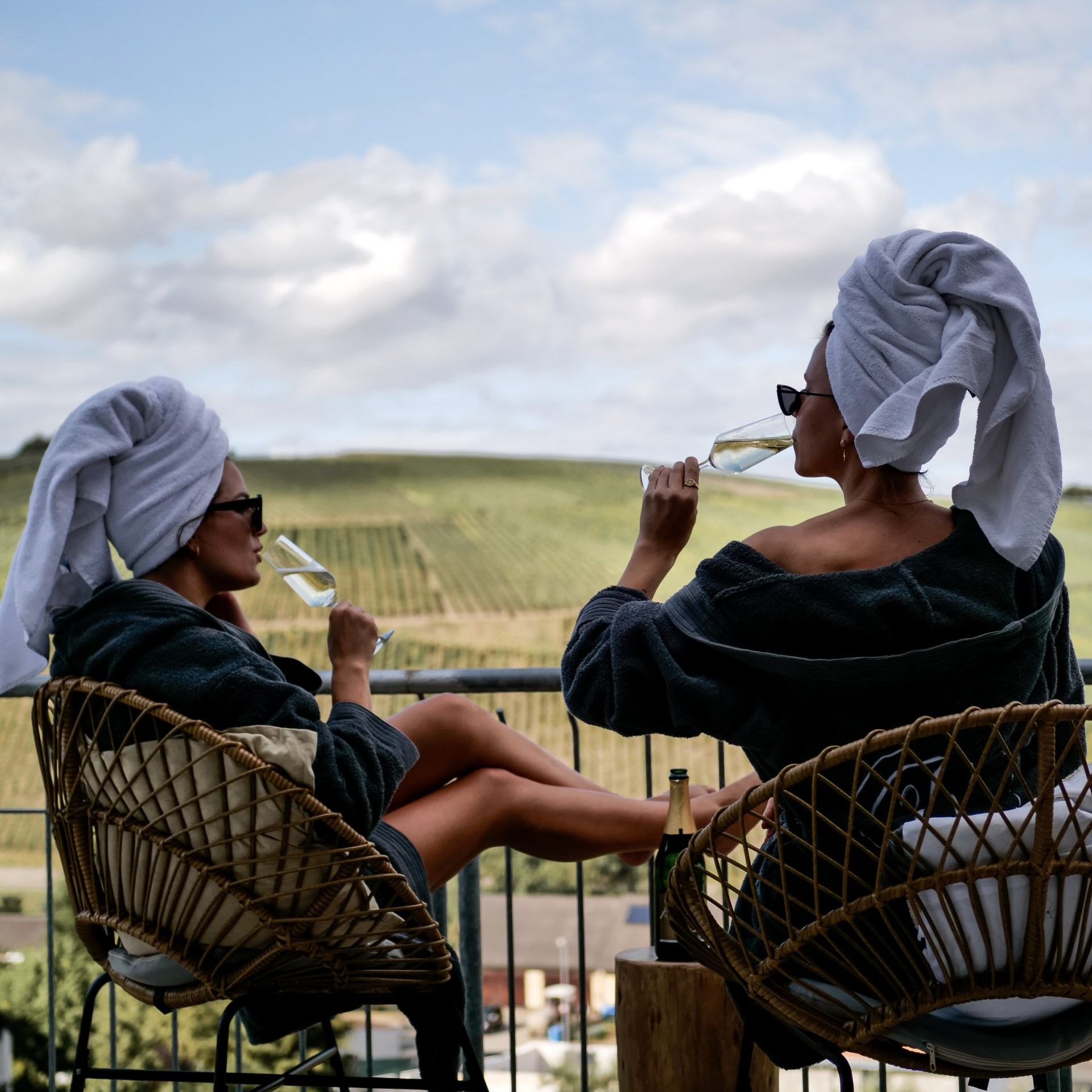 Zwei Frauen sitzen auf einem Balkon und trinken Wein.