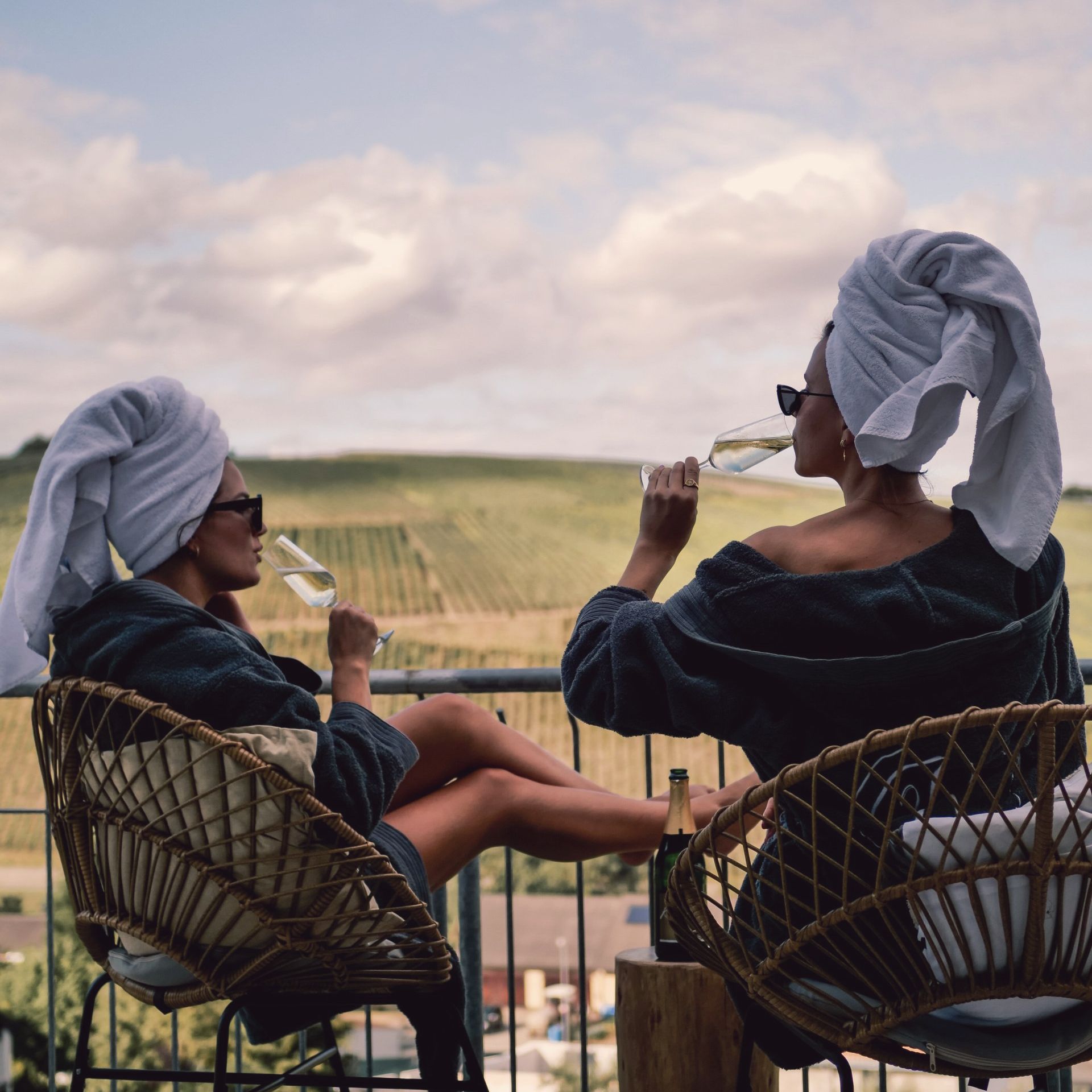 Zwei Frauen sitzen auf einem Balkon und trinken Wein