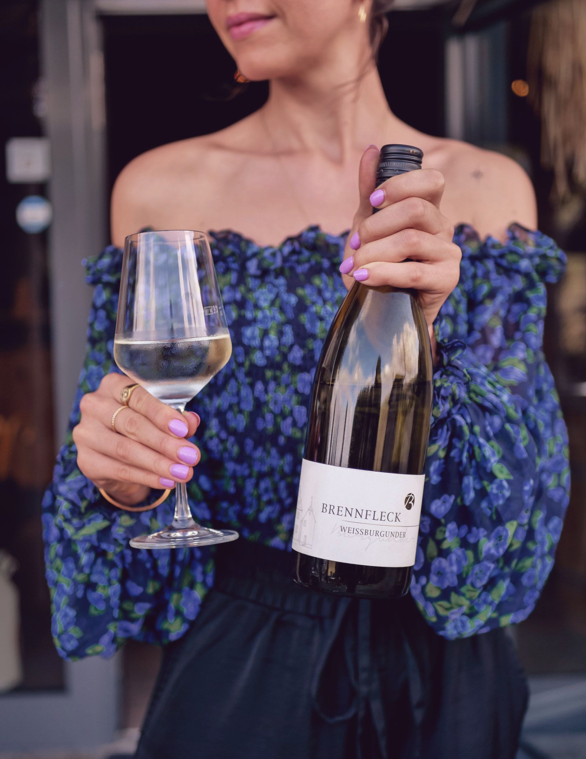 Eine Frau hält eine Flasche Wein und ein Glas Wein.