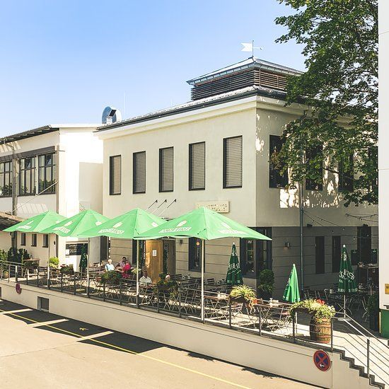 Ein weißes Gebäude mit grünen Sonnenschirmen davor