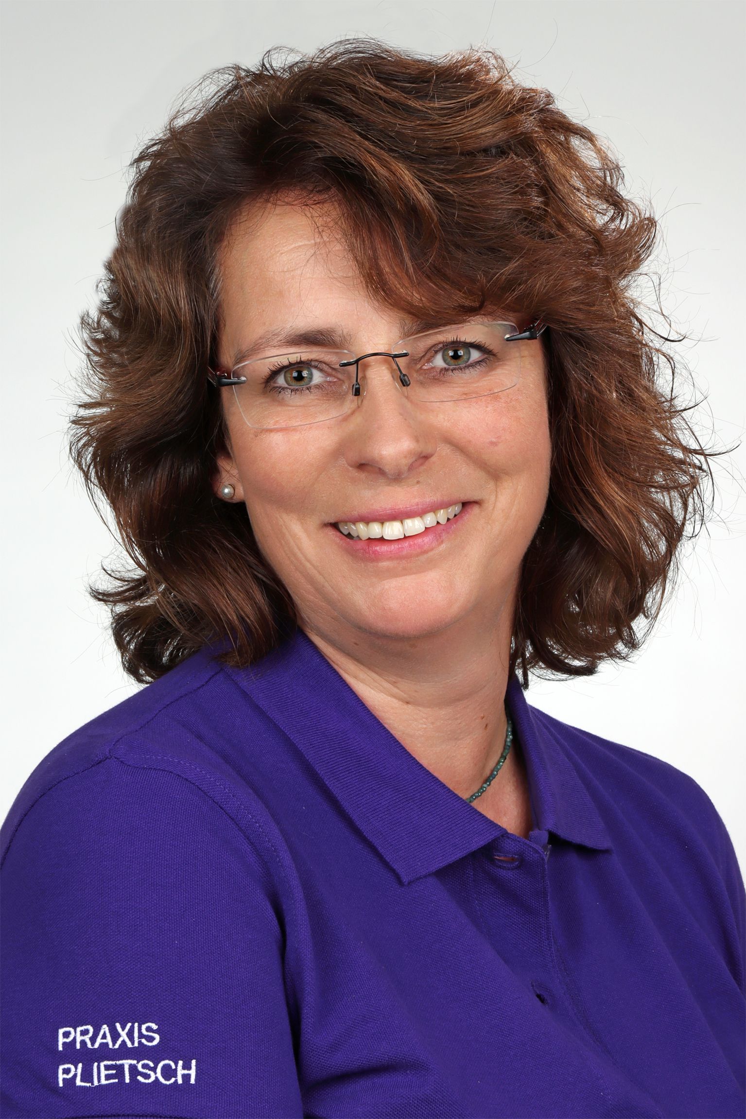 Frau mit Brille und lila Hemd lächelt, Logo „Praxis Puetsch“ sichtbar.