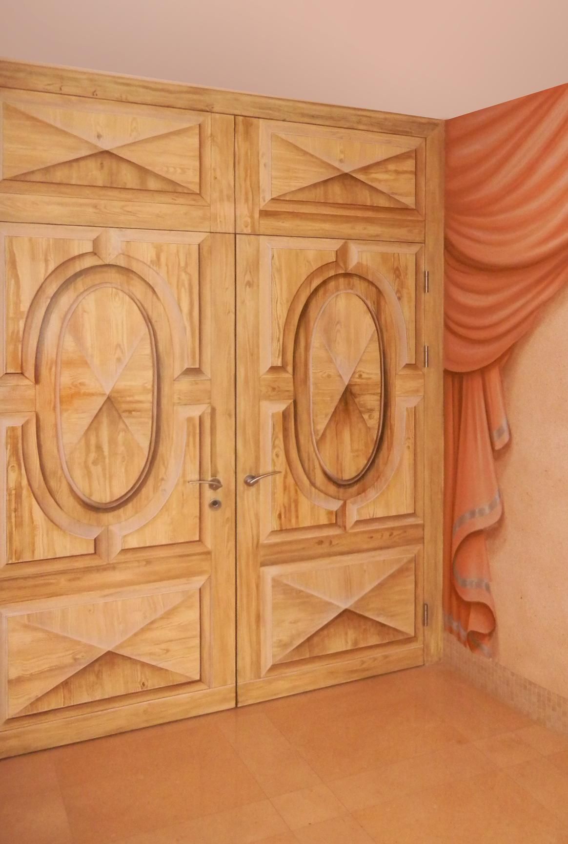 Una coppia di porte in legno con un dipinto sul muro dietro di esse.