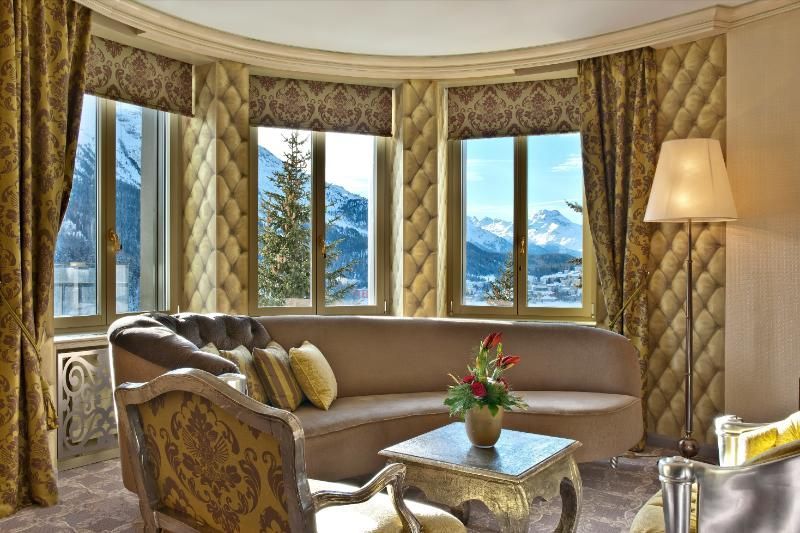 Un soggiorno con divano, sedie e tavolo con vista sulle montagne.