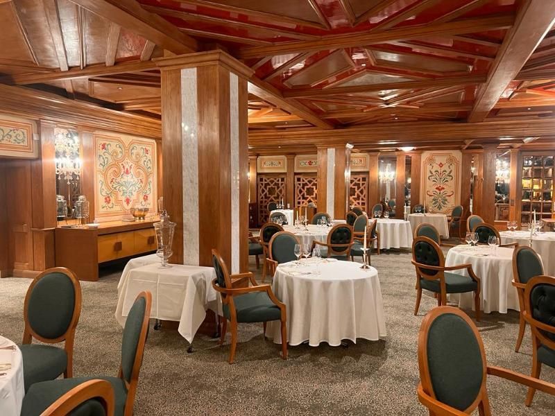 Un'ampia sala da pranzo con tavoli e sedie e soffitto in legno.