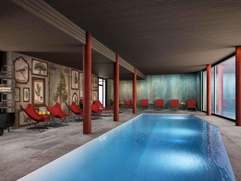 Rappresentazione artistica di una piscina coperta con sedie rosse.