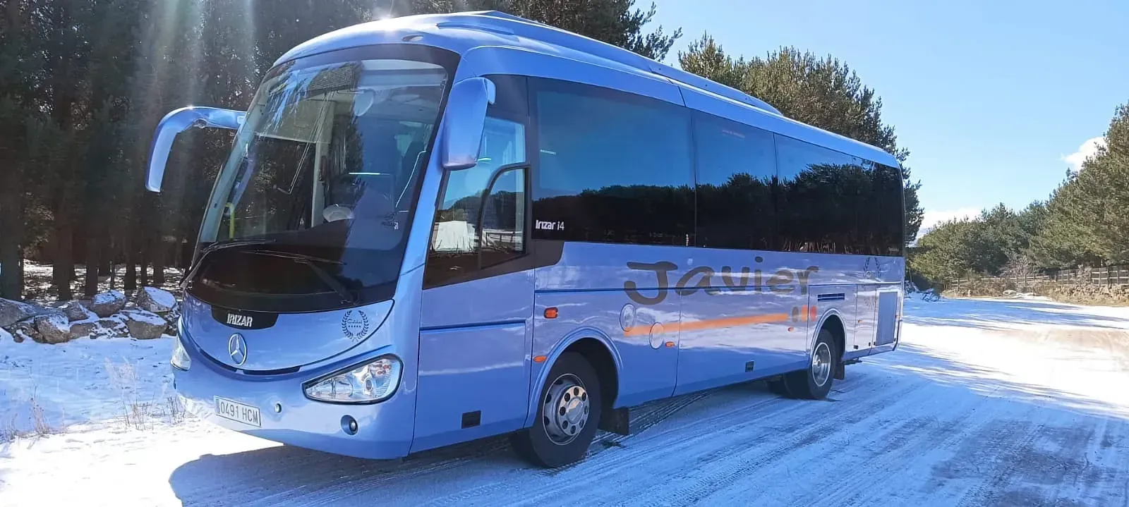 Un autobús azul está estacionado en la nieve en una carretera nevada.