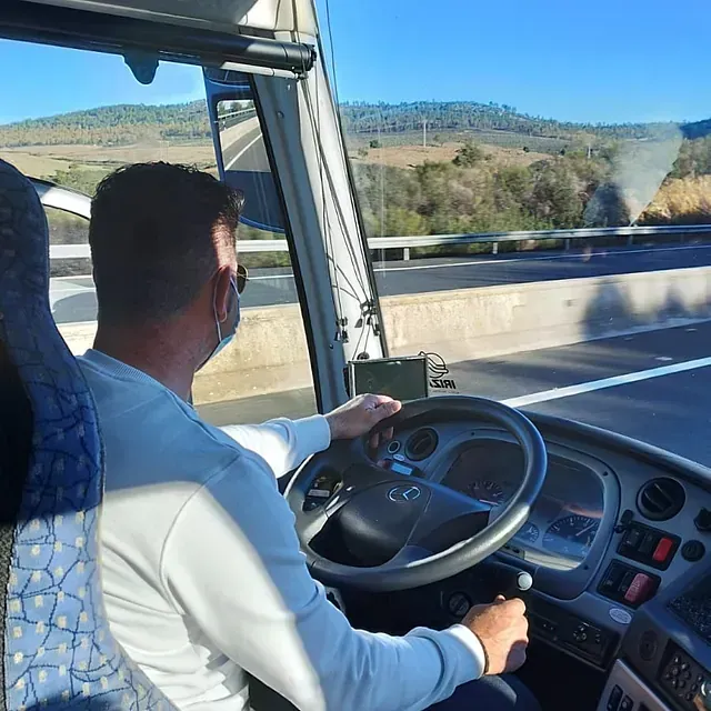 Un hombre que lleva una máscara conduce un autobús en una autopista.
