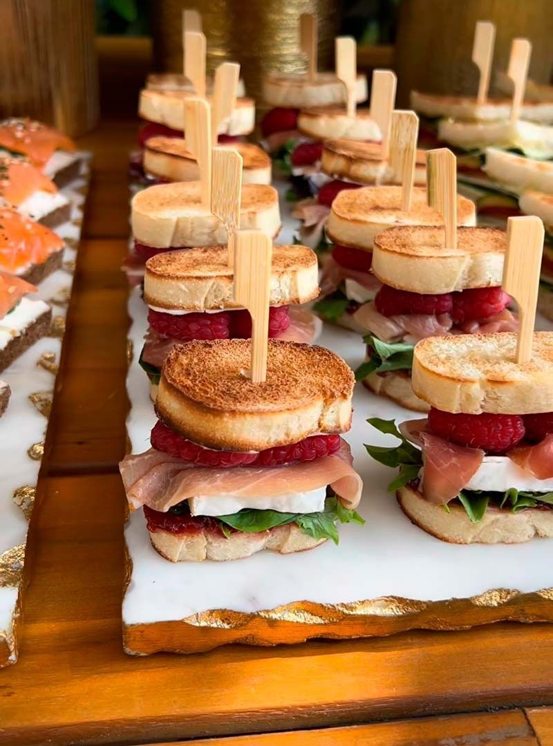 Una bandeja de sándwiches en palillos sobre una mesa de madera.