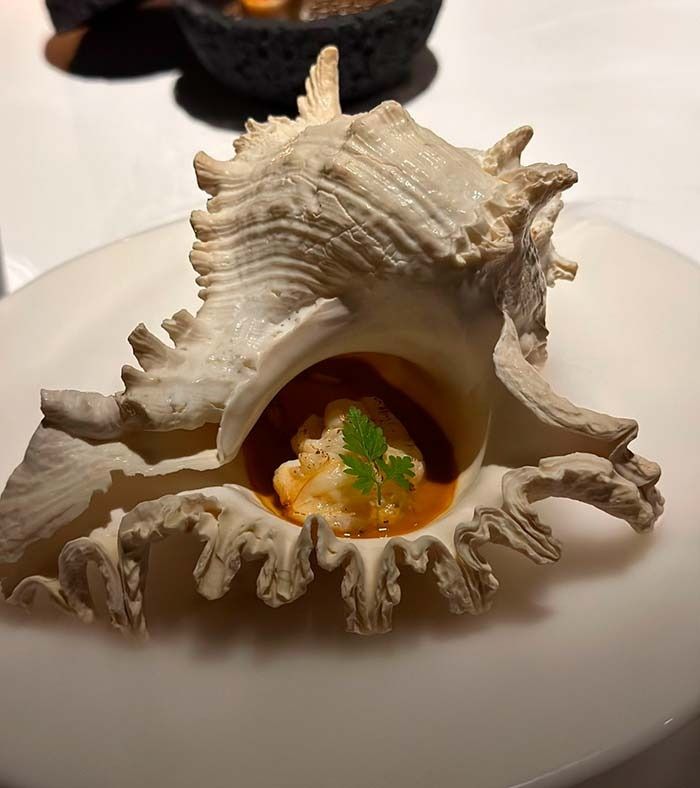 Una concha marina con comida dentro en un plato blanco.