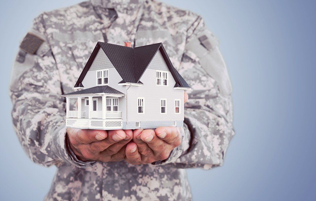 Un militaire qui tient une maquette de maison