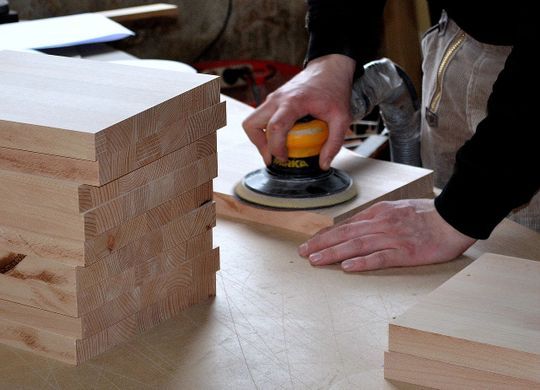 Una persona está lijando un trozo de madera en una mesa.