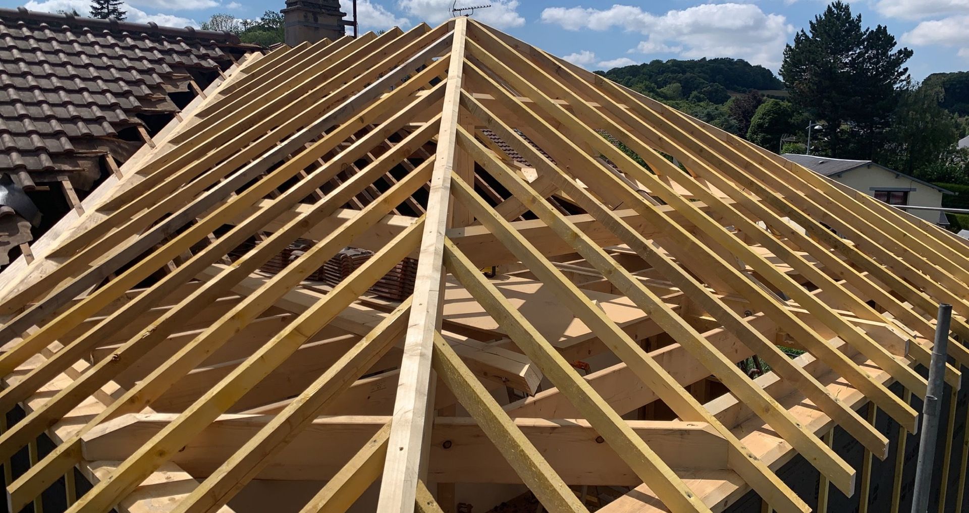 Charpente de toit en bois en cours de construction, avec chevrons et poutres de soutien.