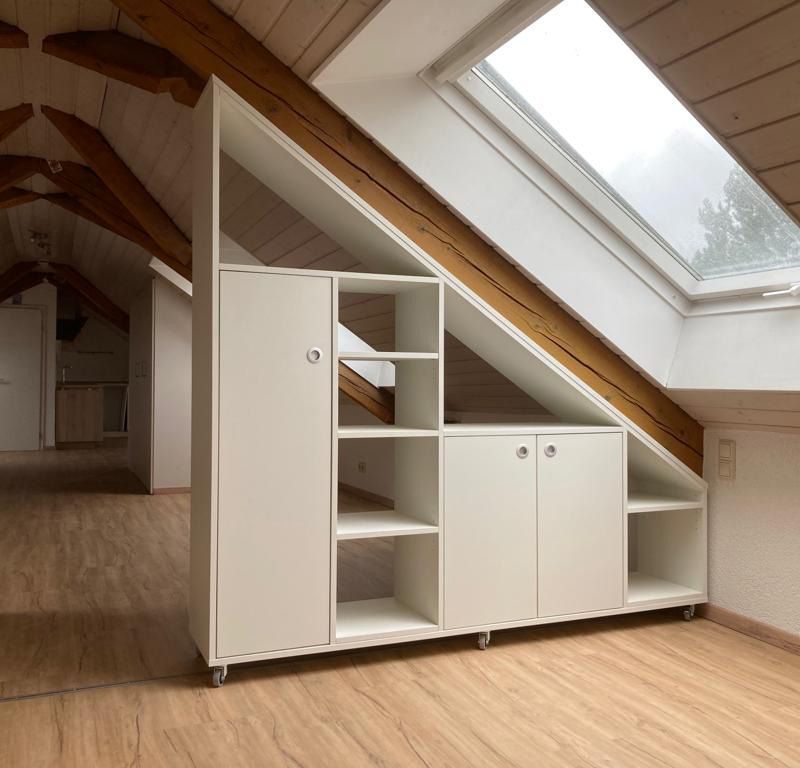 Ein weißes Regal als Raumtrenner an eine Wandschräge angepasst