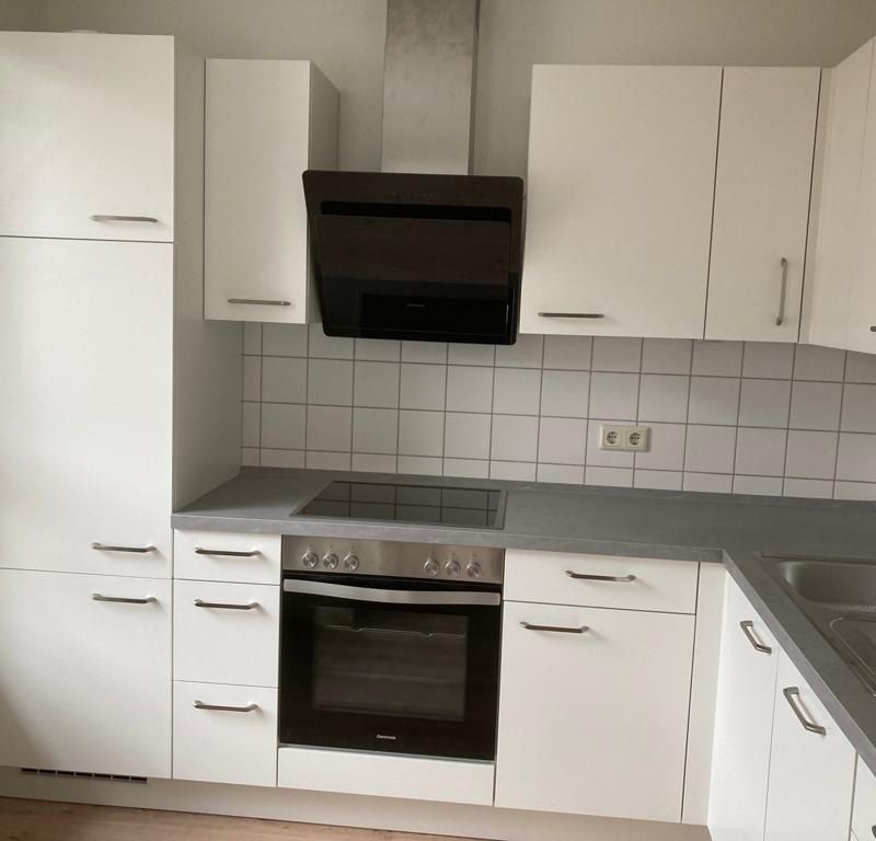 eine Küche mit weißen Schränken und dunklen Arbeitsplatten