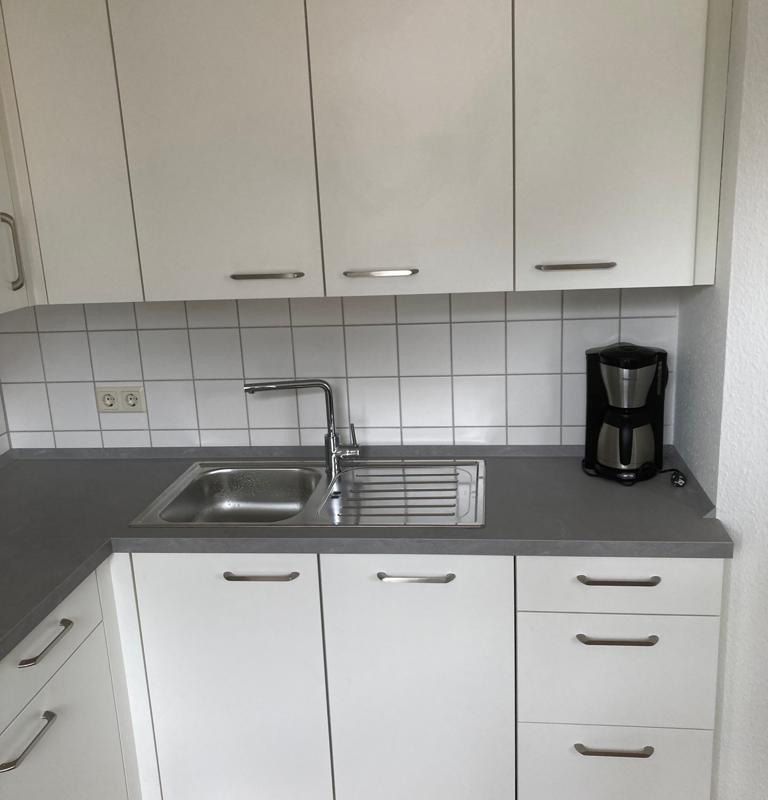 eine Küche mit weißen Schränken und dunklen Arbeitsplatten